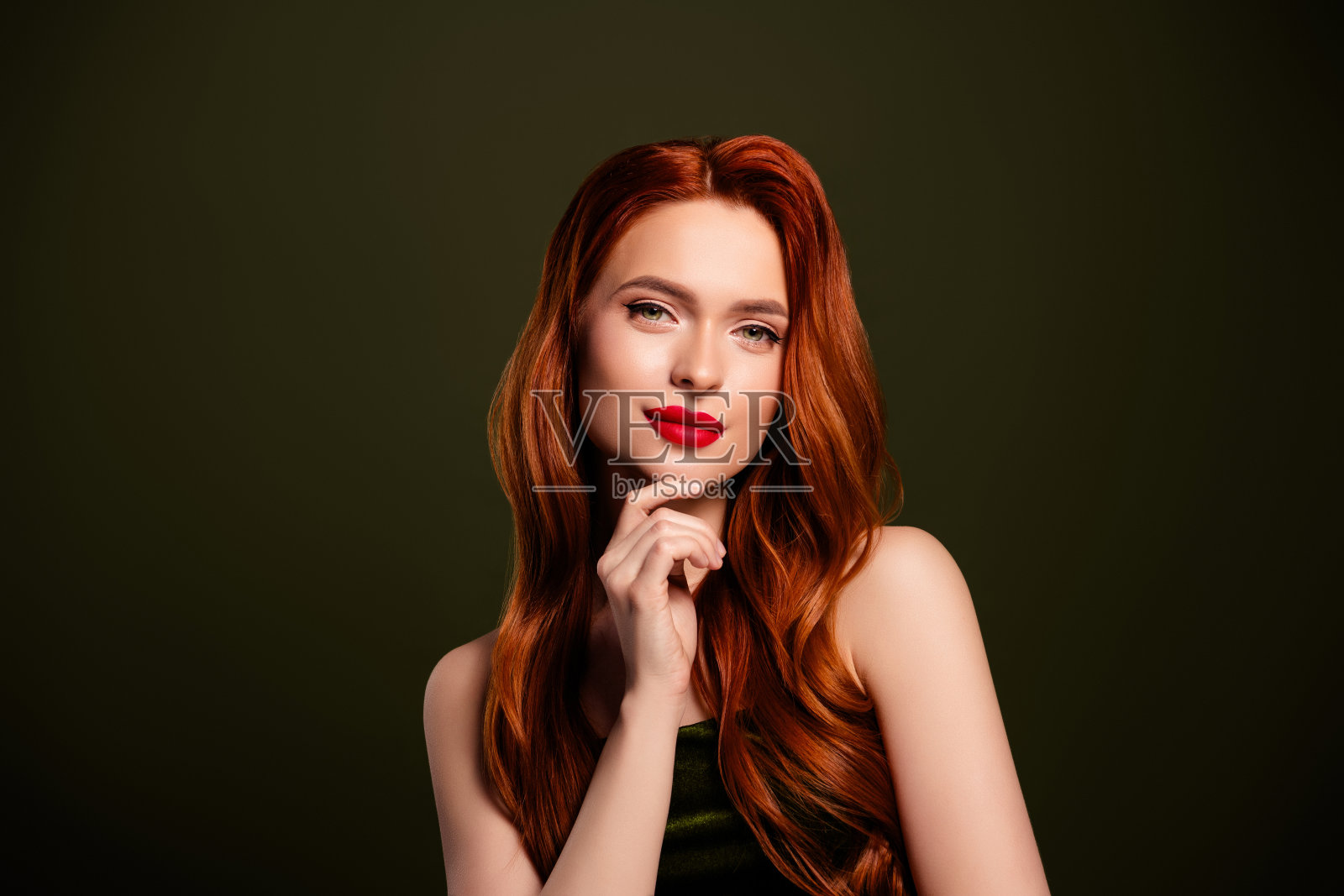 吸引人的富有女神在卡其色背景下触摸下巴，享受奢华的夜总会派对生活照片摄影图片