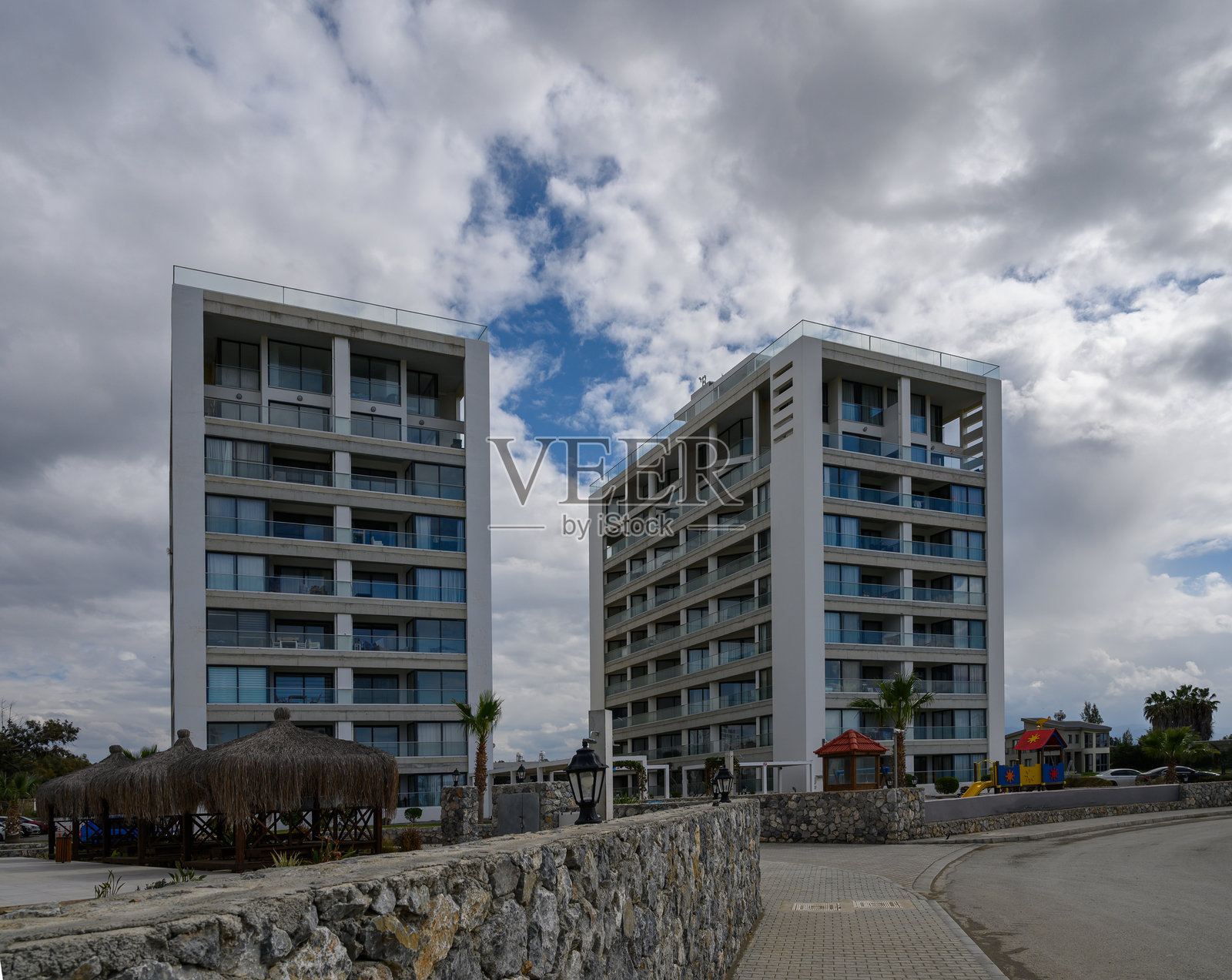 现代建筑在海滨开发区的戏剧性天空下高耸入云，周围有棕榈树。照片摄影图片