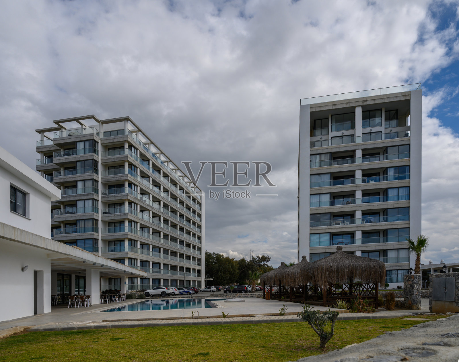 现代度假村建筑在阴云密布的天空下，宁静的泳池边景色，营造出一个宁静的度假胜地。照片摄影图片