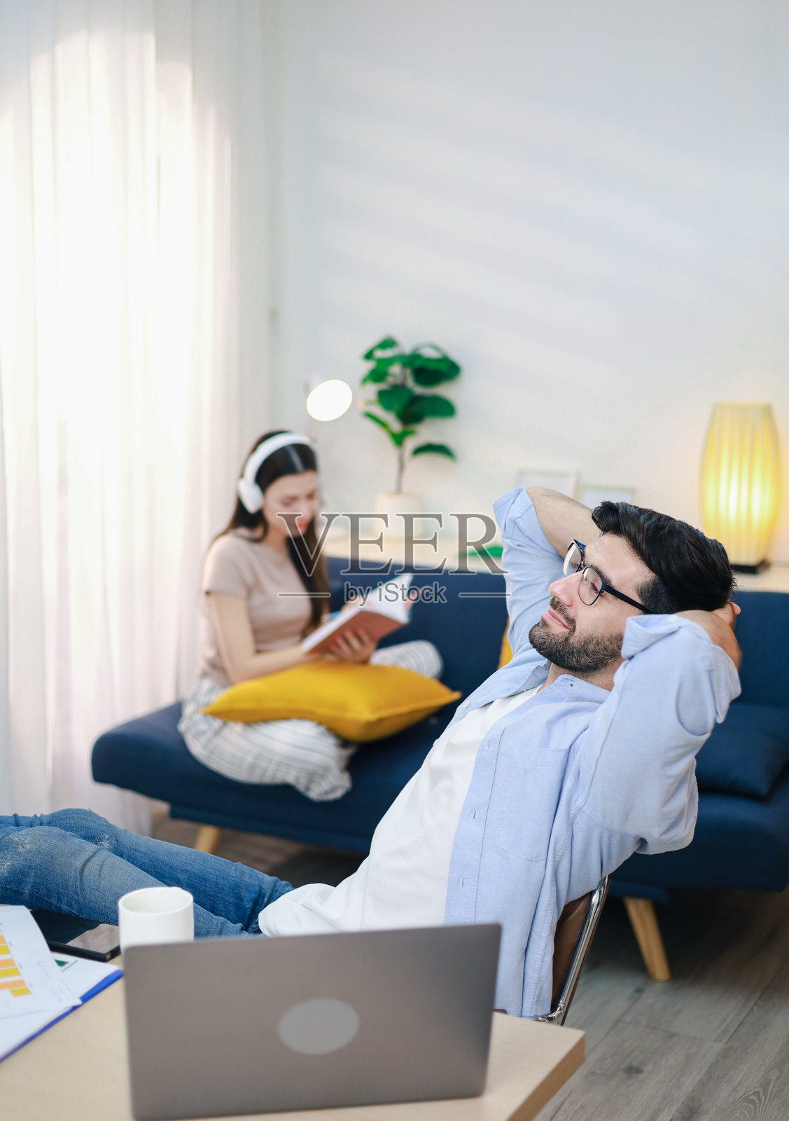 快乐的商人在家办公桌前闭眼，双手放在头后休息。照片摄影图片