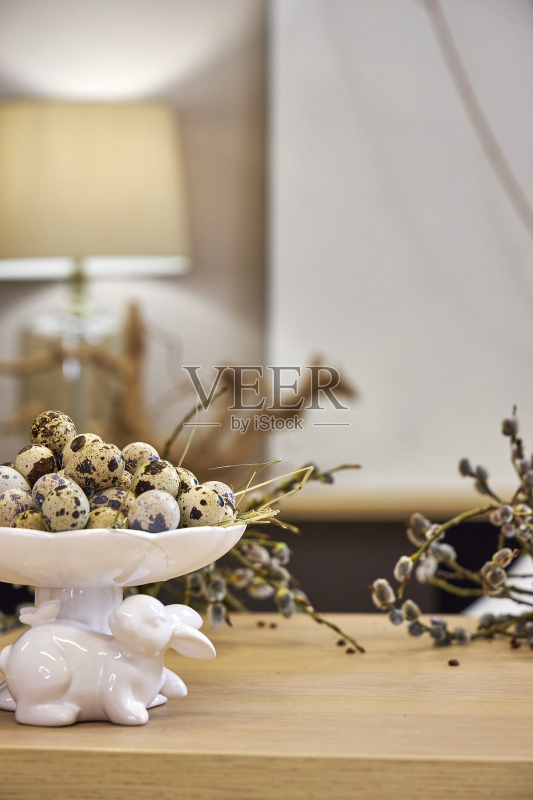 复活节背景的正面视图，桌上摆放着柳枝和鹌鹑蛋，室内环境。照片摄影图片