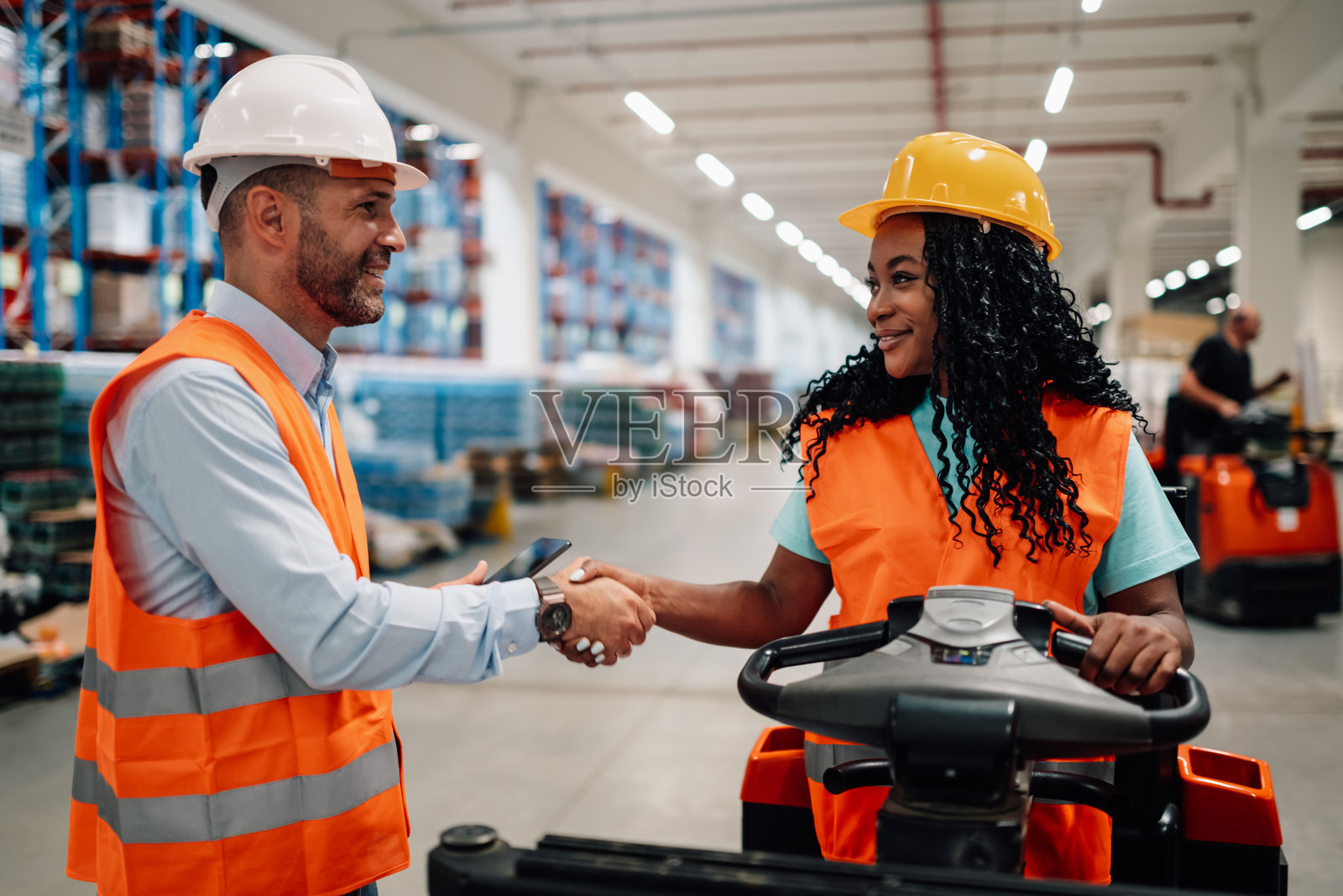 经理和叉车操作员在仓库握手照片摄影图片