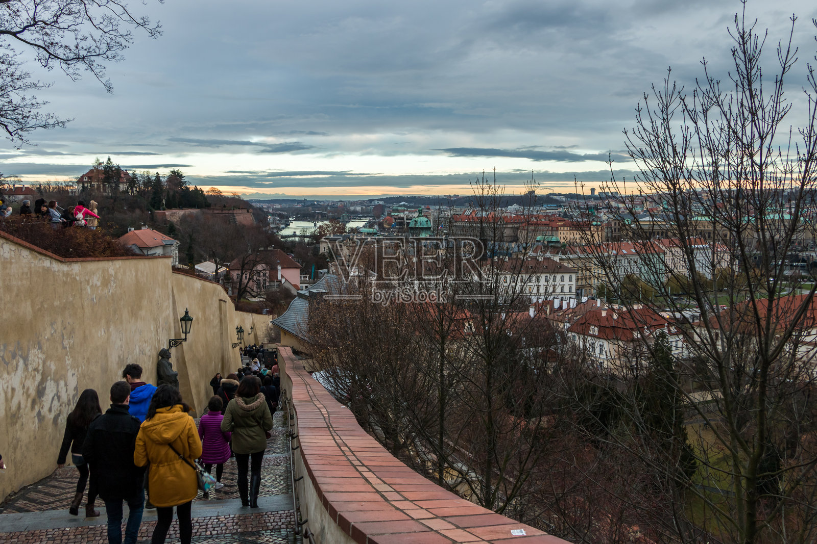 冬季傍晚的布拉格城堡山。游客们欣赏老城区和历史桥梁的美丽城市景观。色彩斑斓的城市风景,捷克共和国布拉格。照片摄影图片