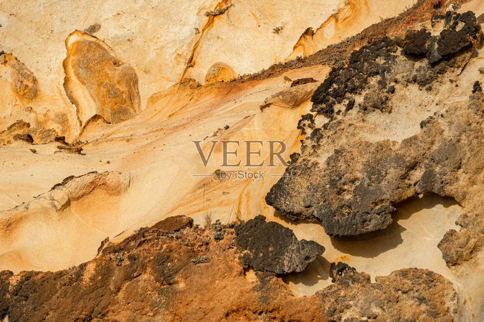 自然纹理背景，展示了葡萄牙圣克鲁斯的阿斯阿莫埃拉斯和福尔摩萨海滩悬崖上的砂岩岩石，带有线条、曲线和印记。照片摄影图片