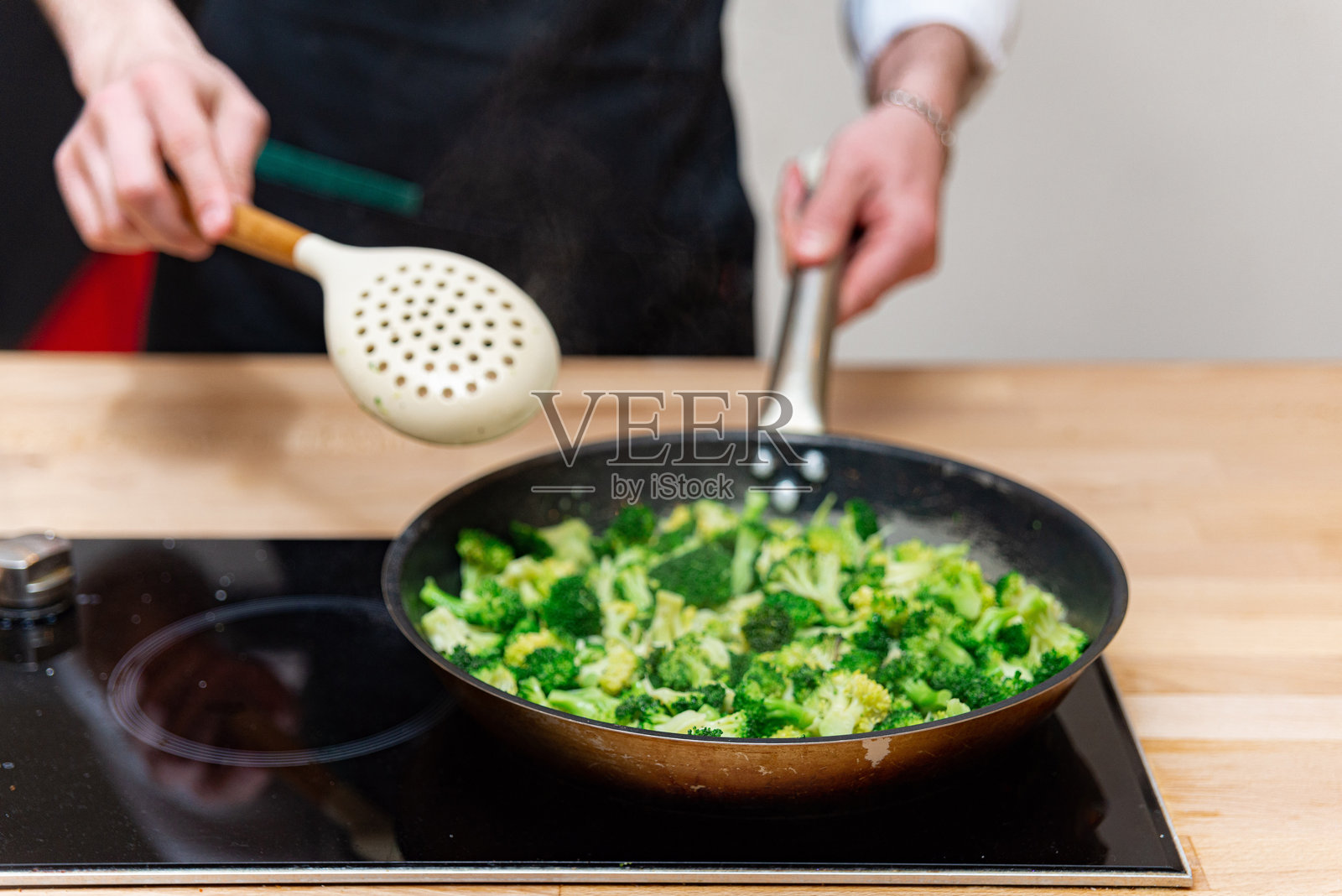厨师在平底锅中烹饪西兰花。照片摄影图片