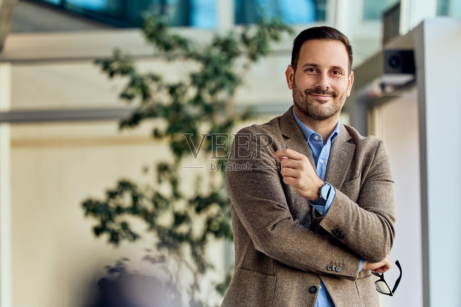 自信的商务专业人士在现代办公室环境中微笑，姿态放松照片摄影图片