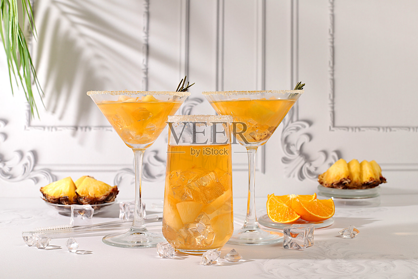 夏季派对概念。柠檬水皇家鸡尾酒，马提尼或由龙舌兰、朗姆酒和伏特加制成的果Punch，配有菠萝片、橙子、冰块和迷迭香。适合酒吧或咖啡馆广告、餐厅菜单的健康饮品。照片摄影图片