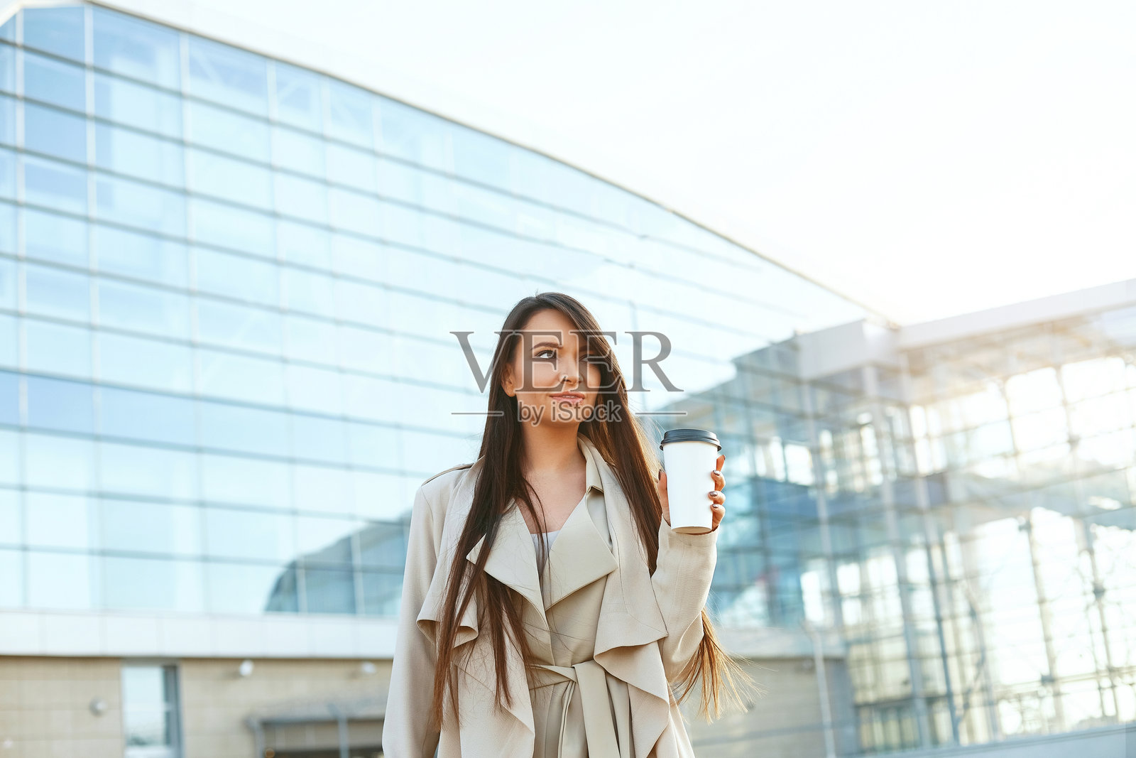 在办公室附近喝咖啡并打电话的女商人。美丽微笑的女性肖像，站在户外，进行电话沟通。照片摄影图片
