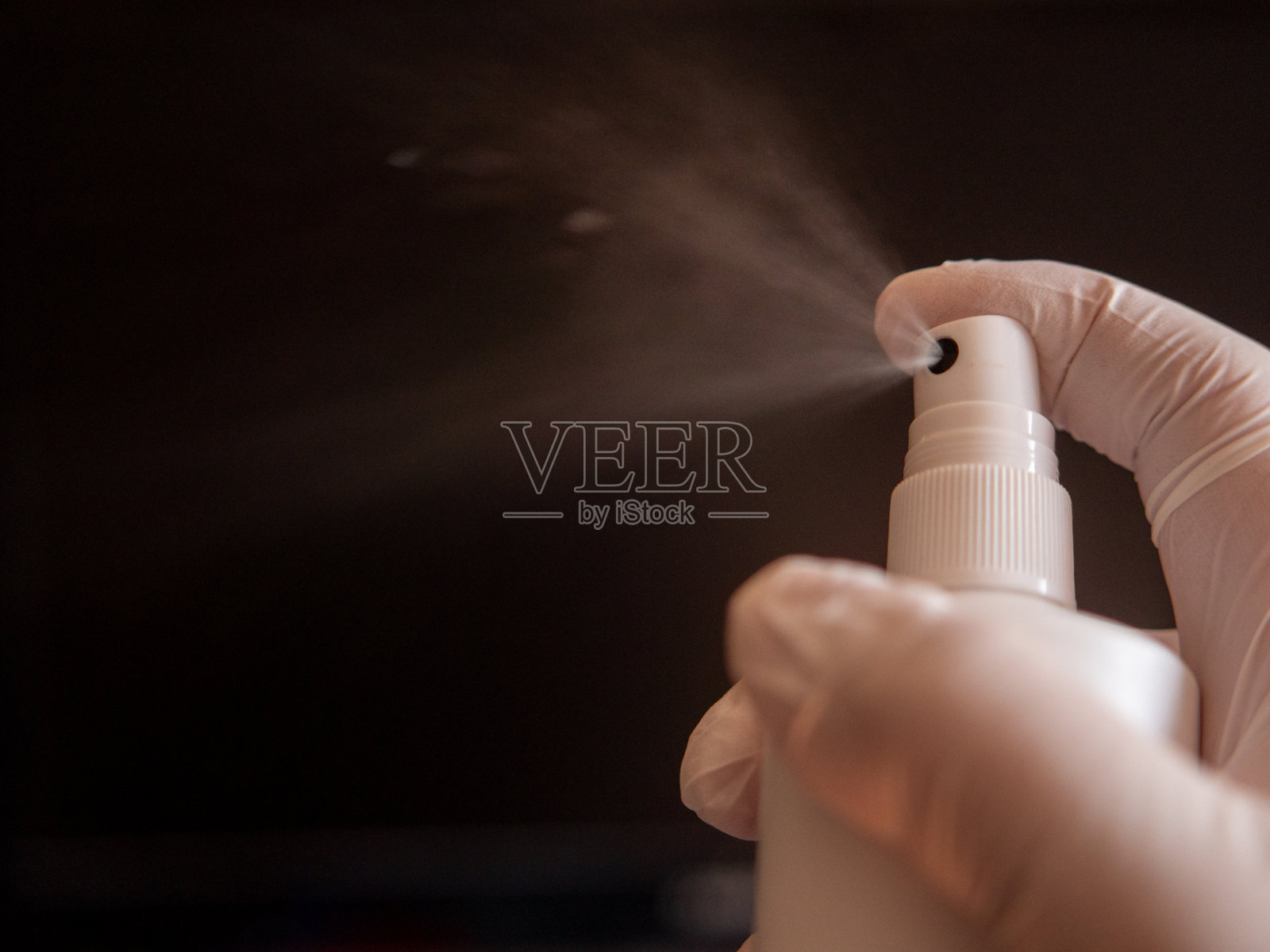 戴着医用手套的手从喷雾瓶中进行消毒照片摄影图片