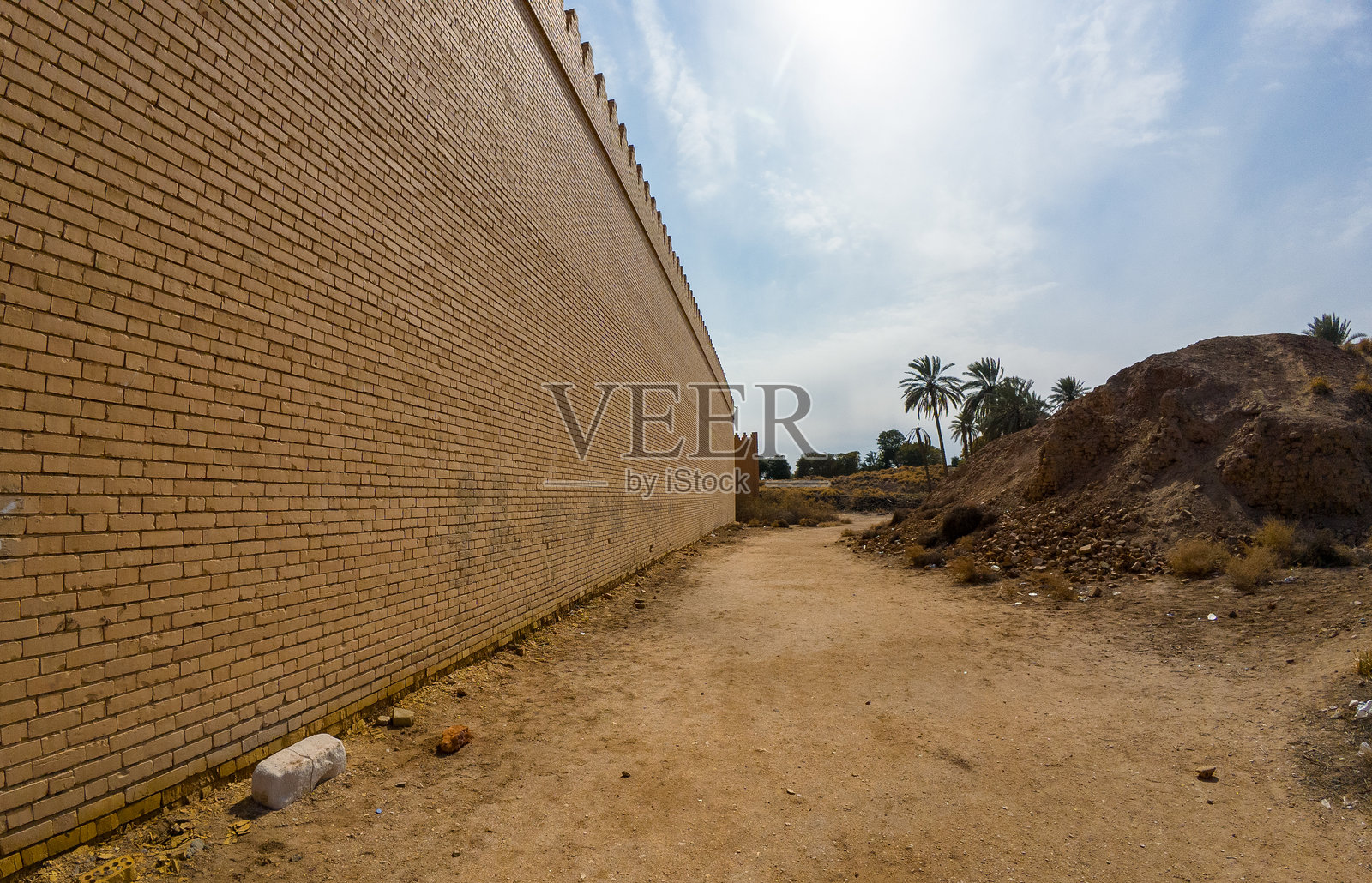 古巴比伦，伊拉克的长砖墙，旁边有棕榈树和泥土小径照片摄影图片