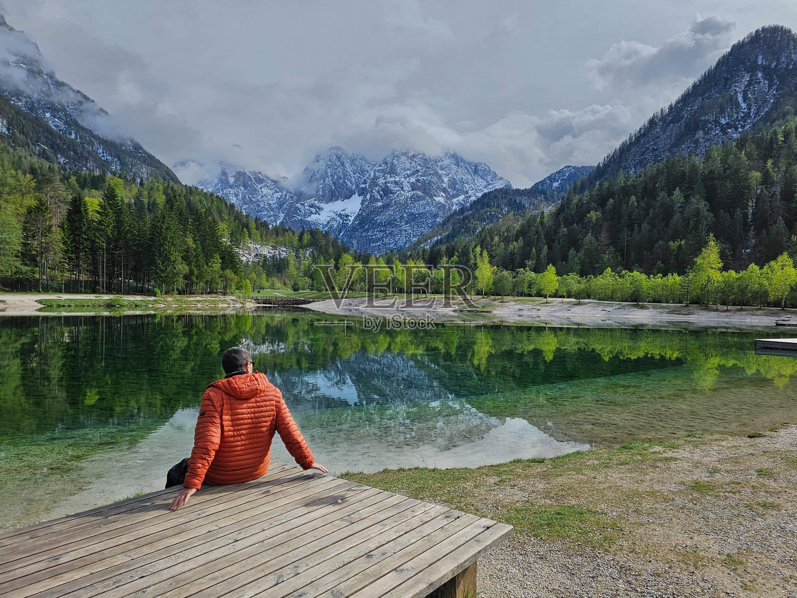 在克拉尼斯卡戈拉的雅斯纳湖上，登山者在木栈道上放松，欣赏特里格拉夫国家公园清澈绿色水面上朱利安阿尔卑斯山的倒影。照片摄影图片