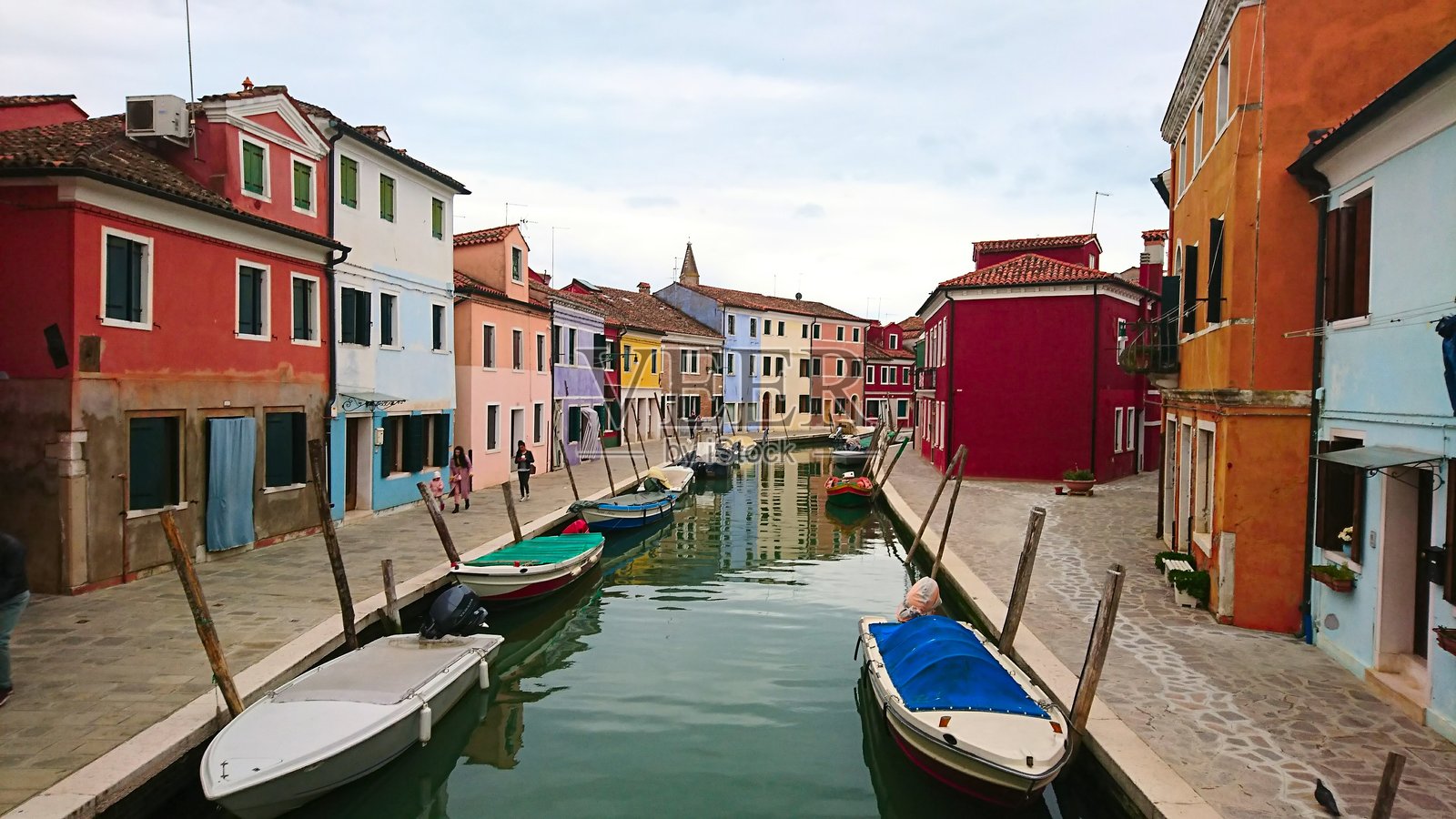 色彩斑斓的房屋沿着运河而建,岸边停靠着小船。照片摄影图片