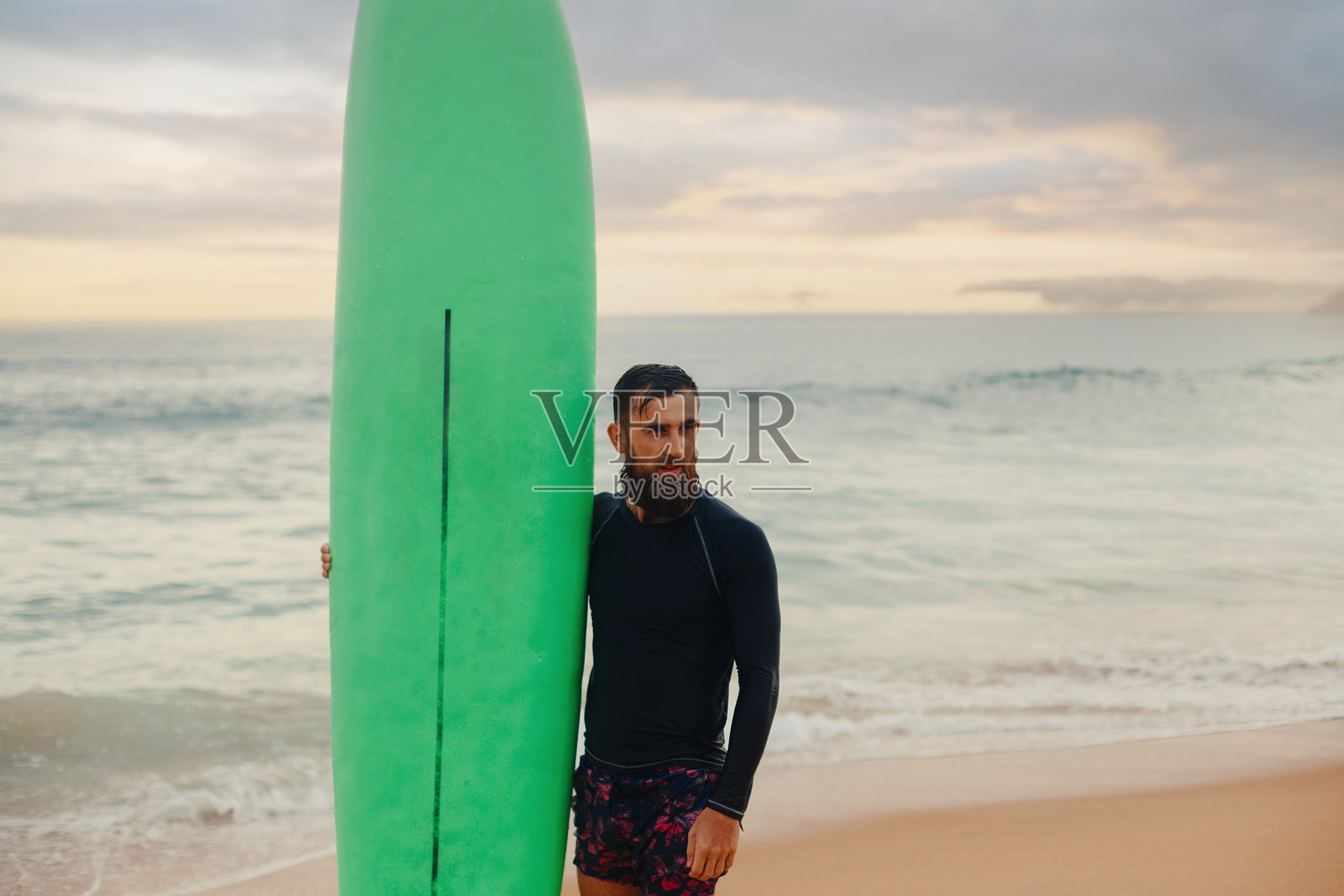 年轻帅气的男性冲浪者手持冲浪板，走在海边的沙滩上，享受着美丽的海景。夏天，假期，海洋。照片摄影图片