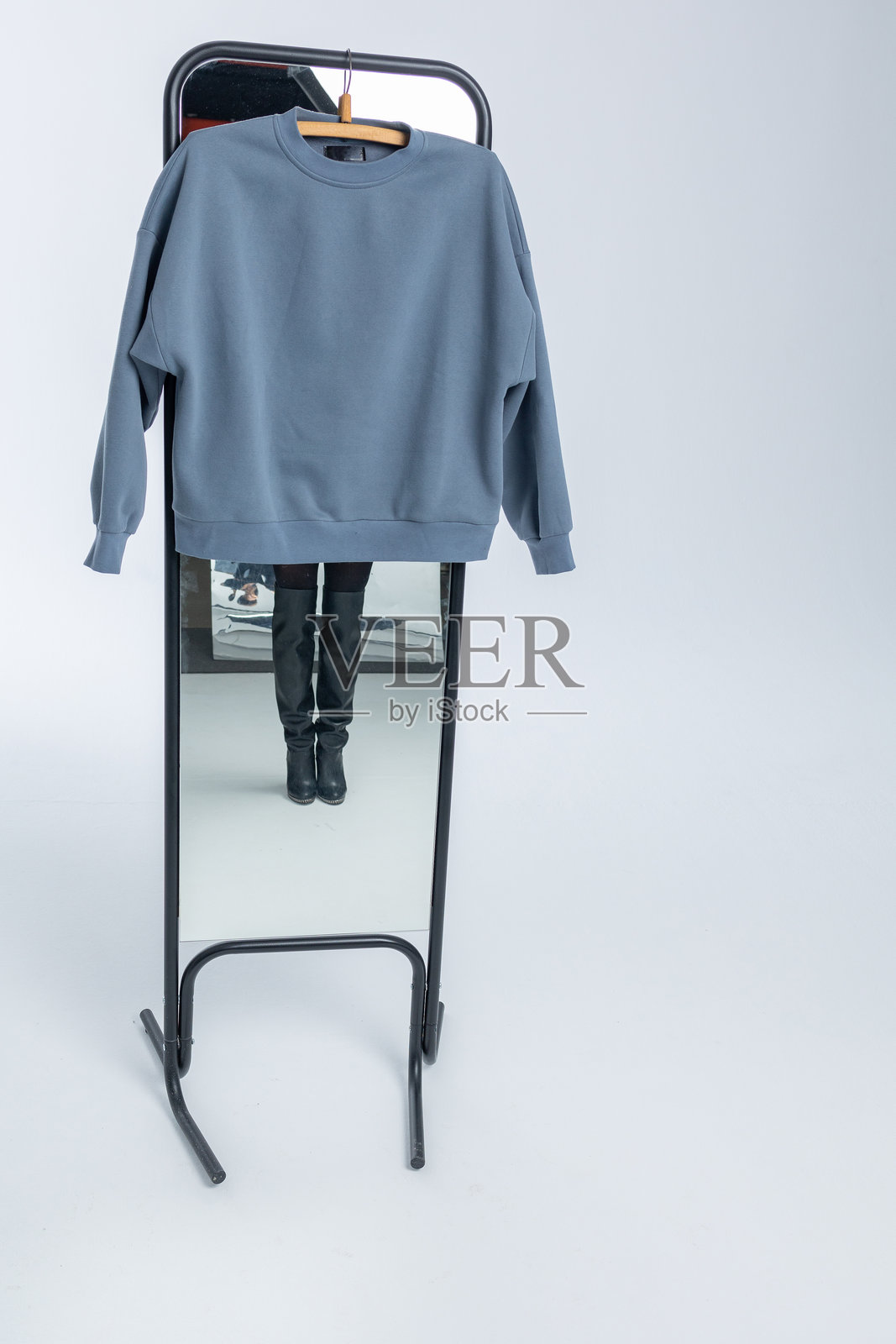 灰色卫衣挂在浅色背景上。竖版照片。照片摄影图片