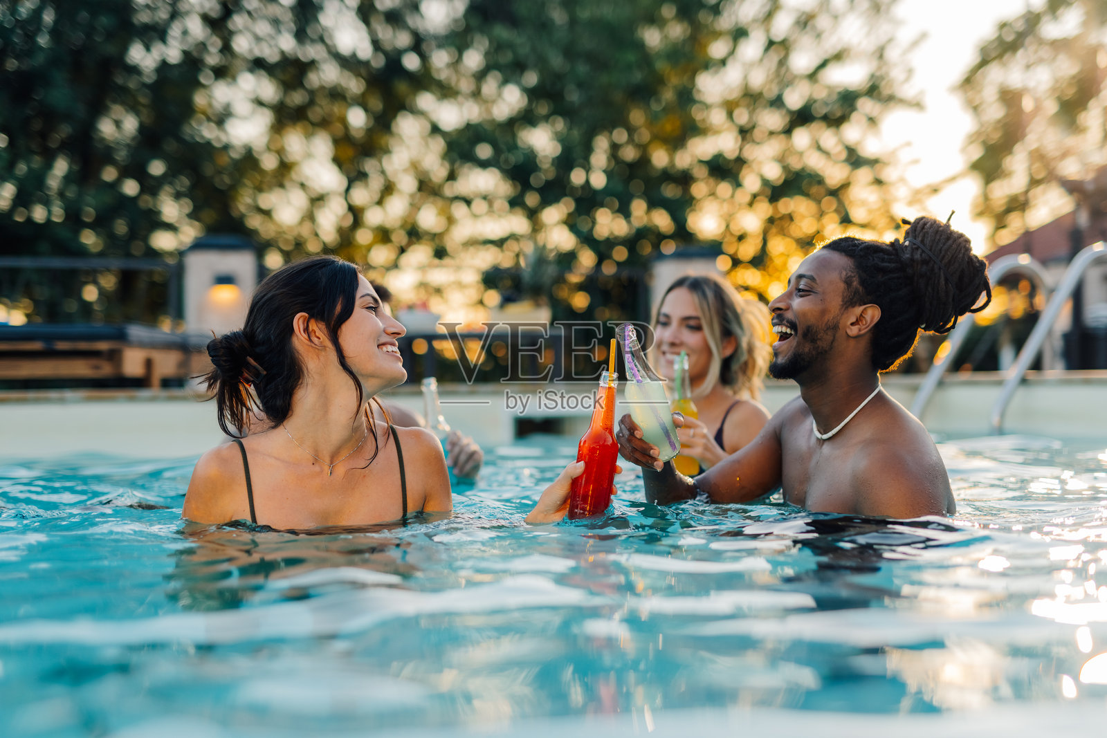 朋友们在日落时分举杯庆祝，享受夏季泳池派对照片摄影图片