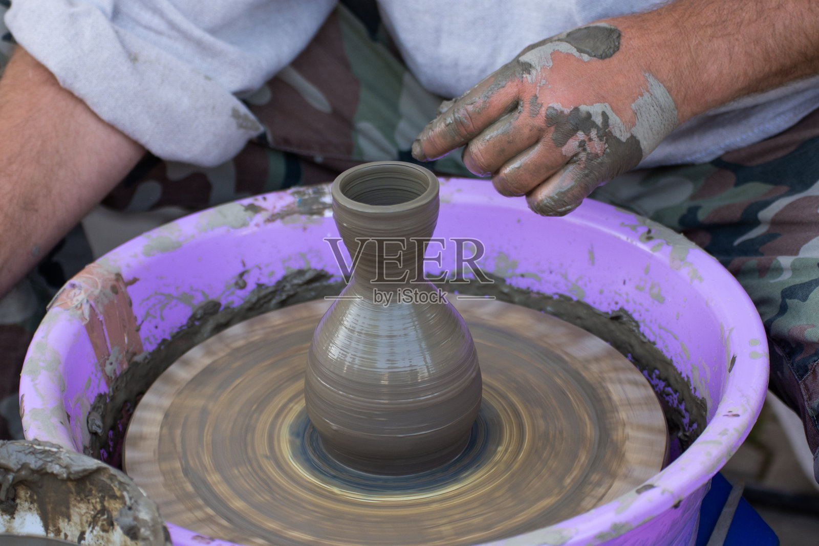 陶艺家的手在旋转的陶轮上制作一个陶罐。照片摄影图片