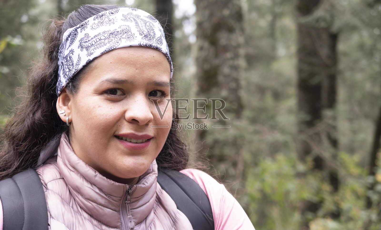 特写镜头中的女性微笑着面对镜头，背景是森林。照片摄影图片