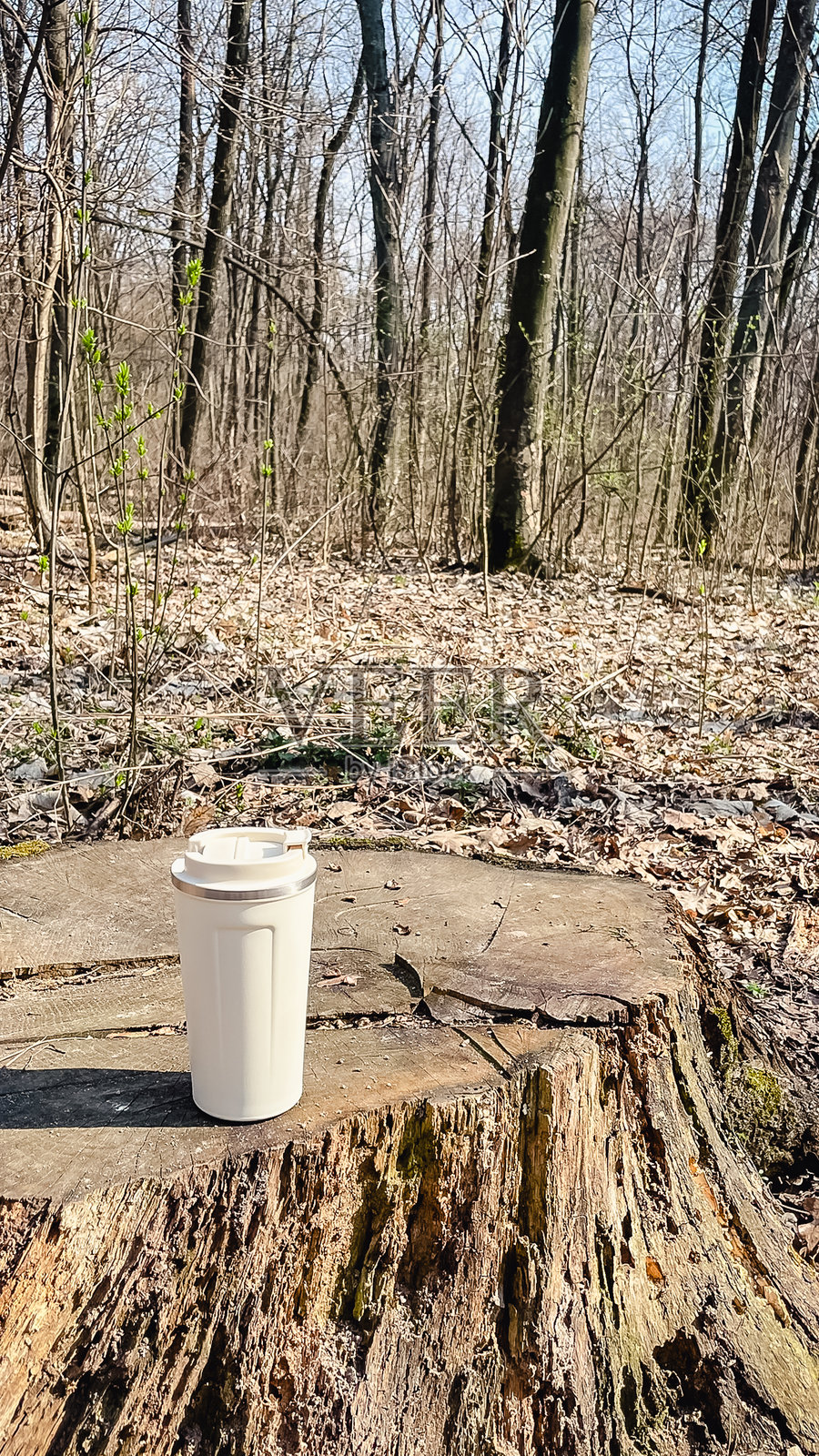 手中拿着米色保温杯在公园散步照片摄影图片