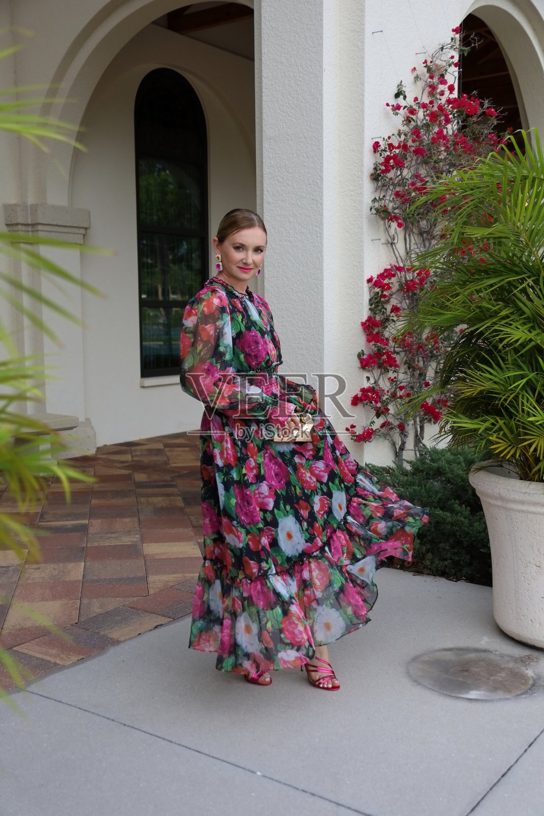 年轻美丽的女性穿着印花长裙，手提金色手袋。照片摄影图片