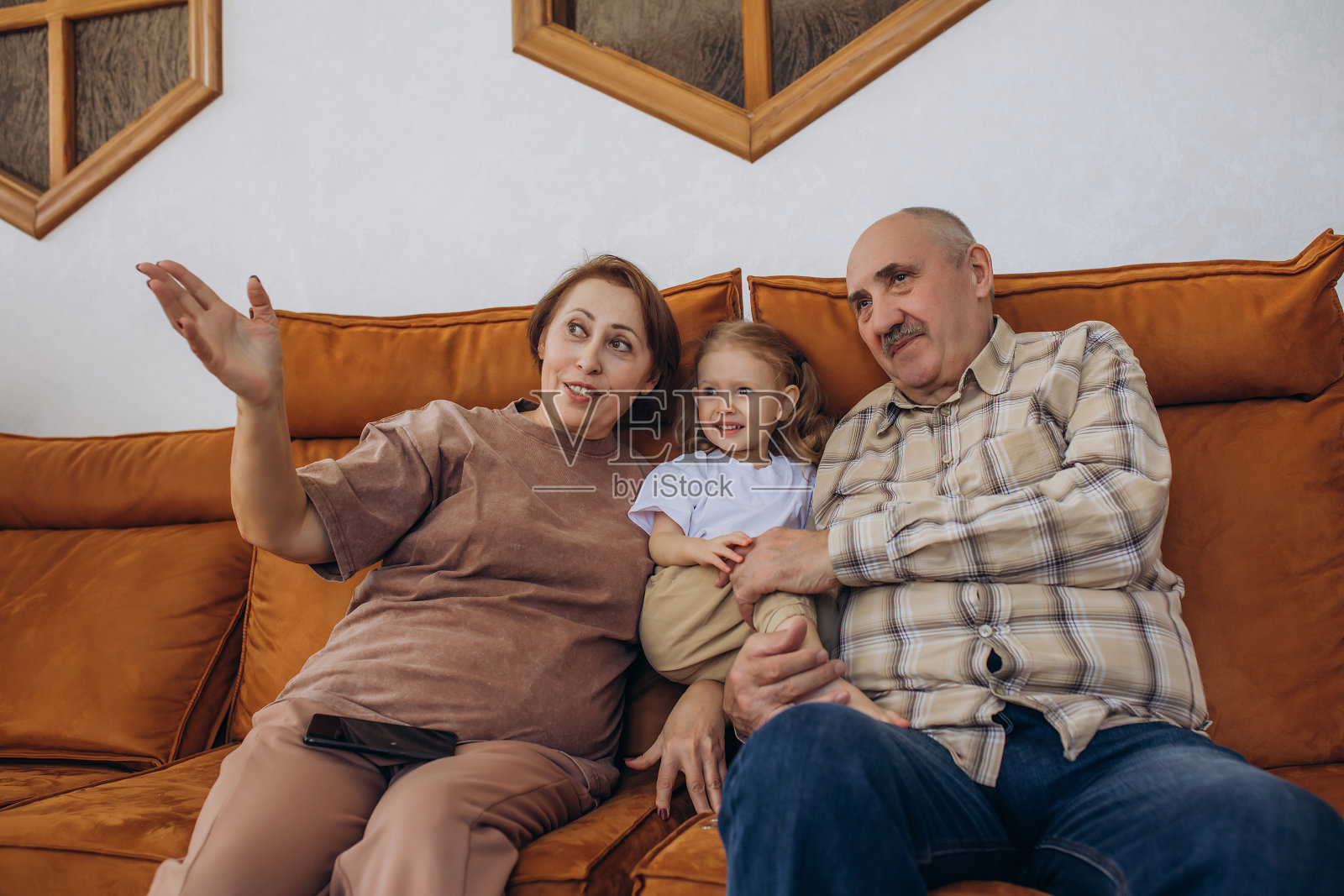 祖母和祖父与他们的婴儿 granddaughter 一起坐在家里的沙发上照片摄影图片