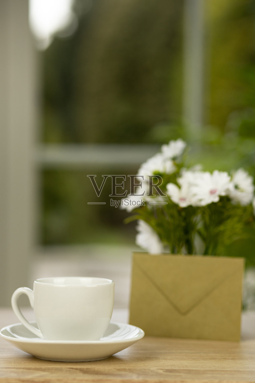 一杯咖啡、鲜花和一个信封。办公桌上放着一杯咖啡。照片摄影图片