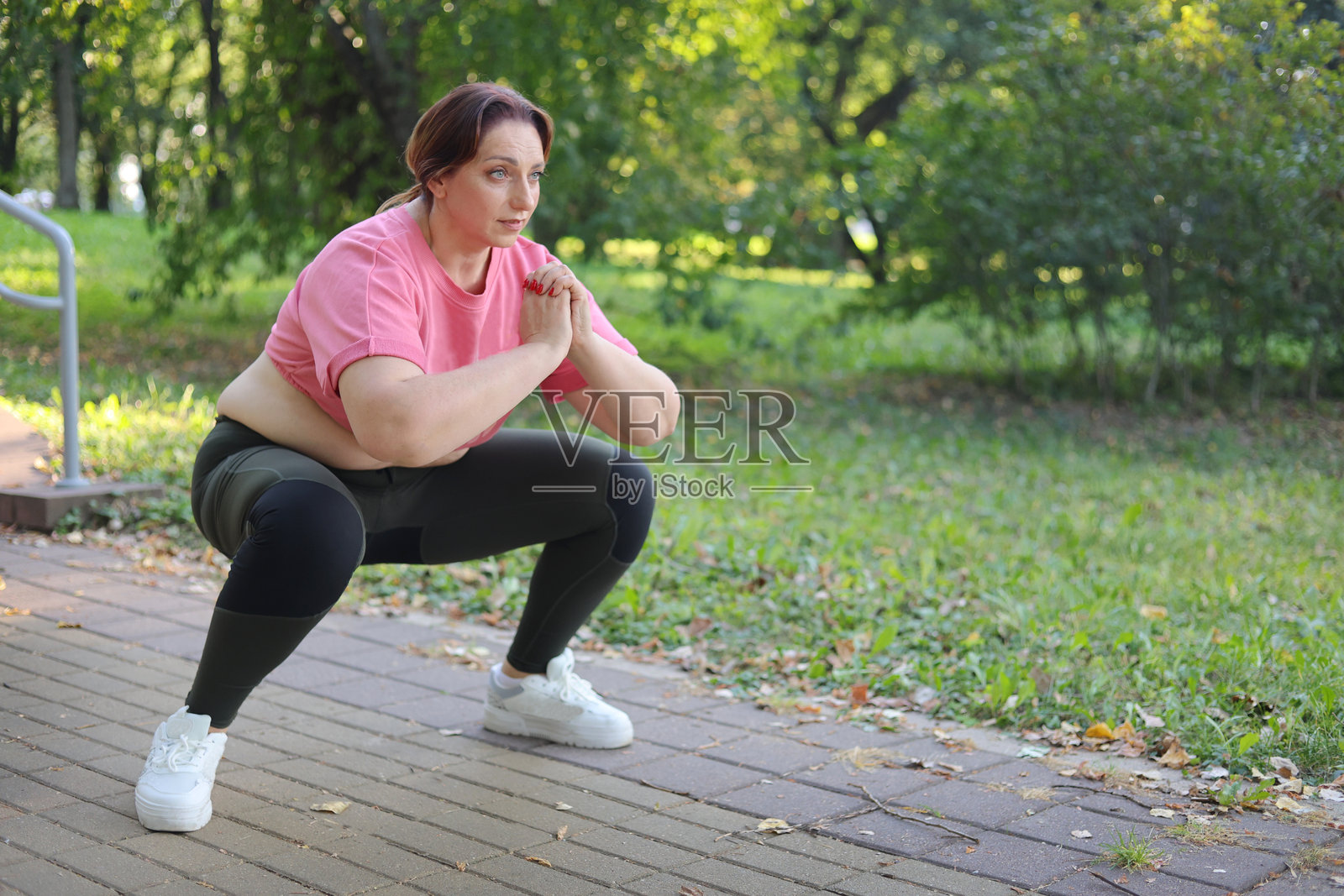公园里做深蹲的老年女性健身者照片摄影图片