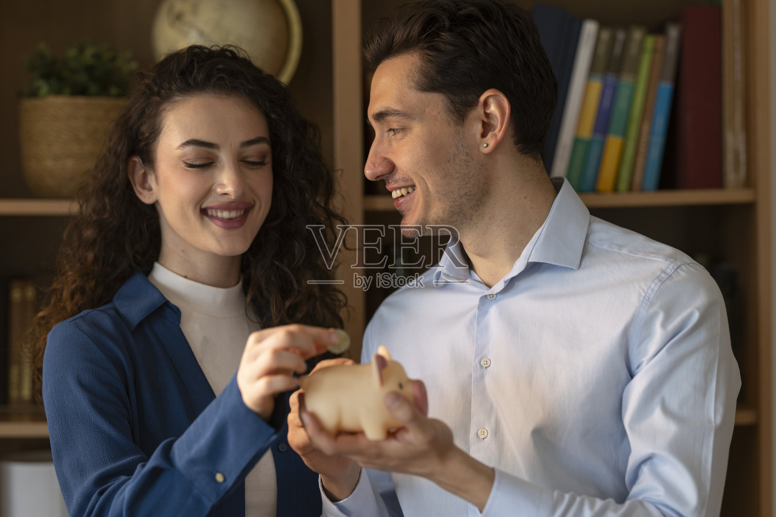 年轻情侣将硬币放入储蓄罐，规划未来并存钱照片摄影图片