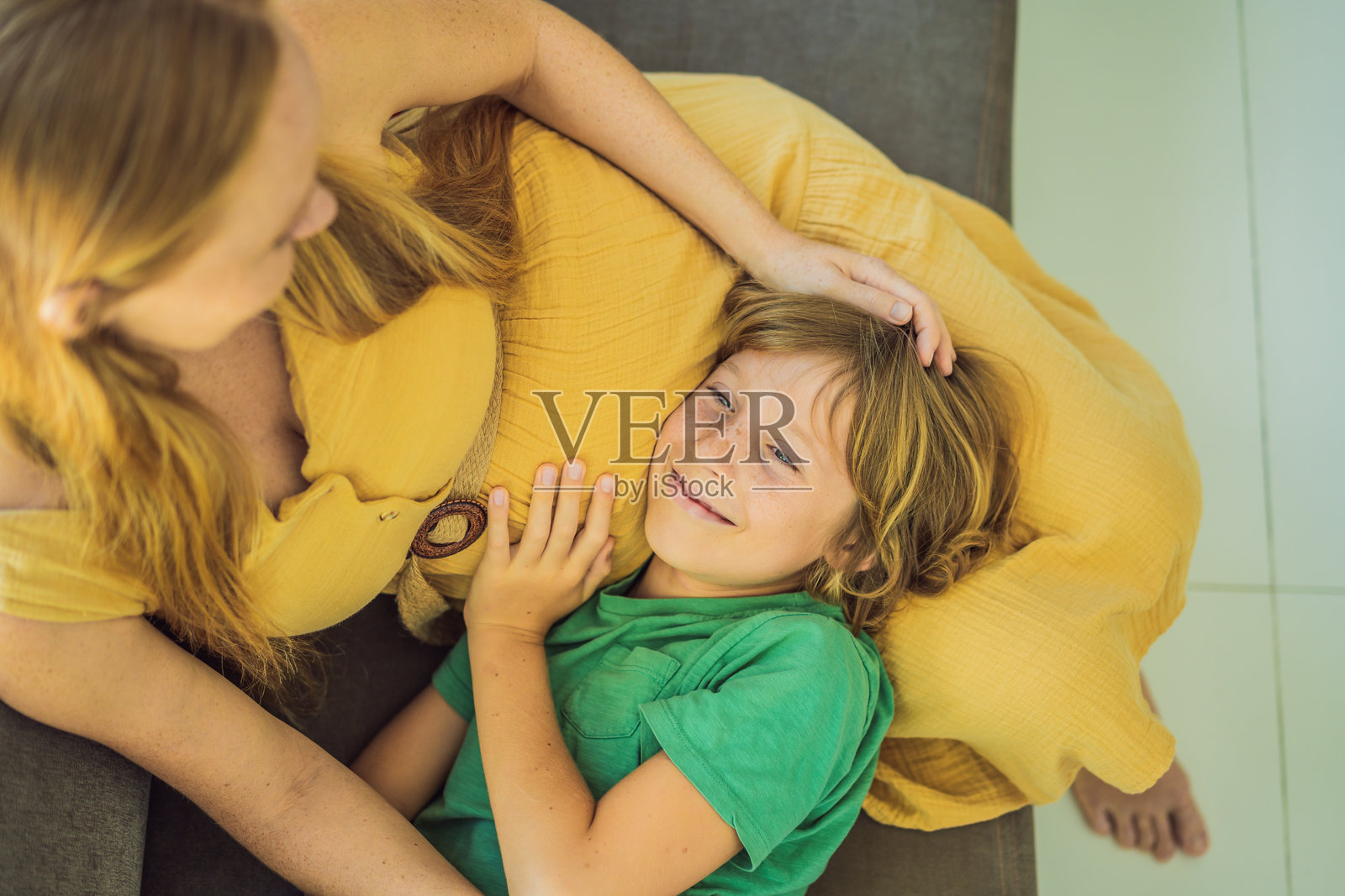 温馨的时刻：怀孕的母亲和她的哥哥坐在沙发上，进行着关于即将到来的怀孕的温柔对话。照片摄影图片