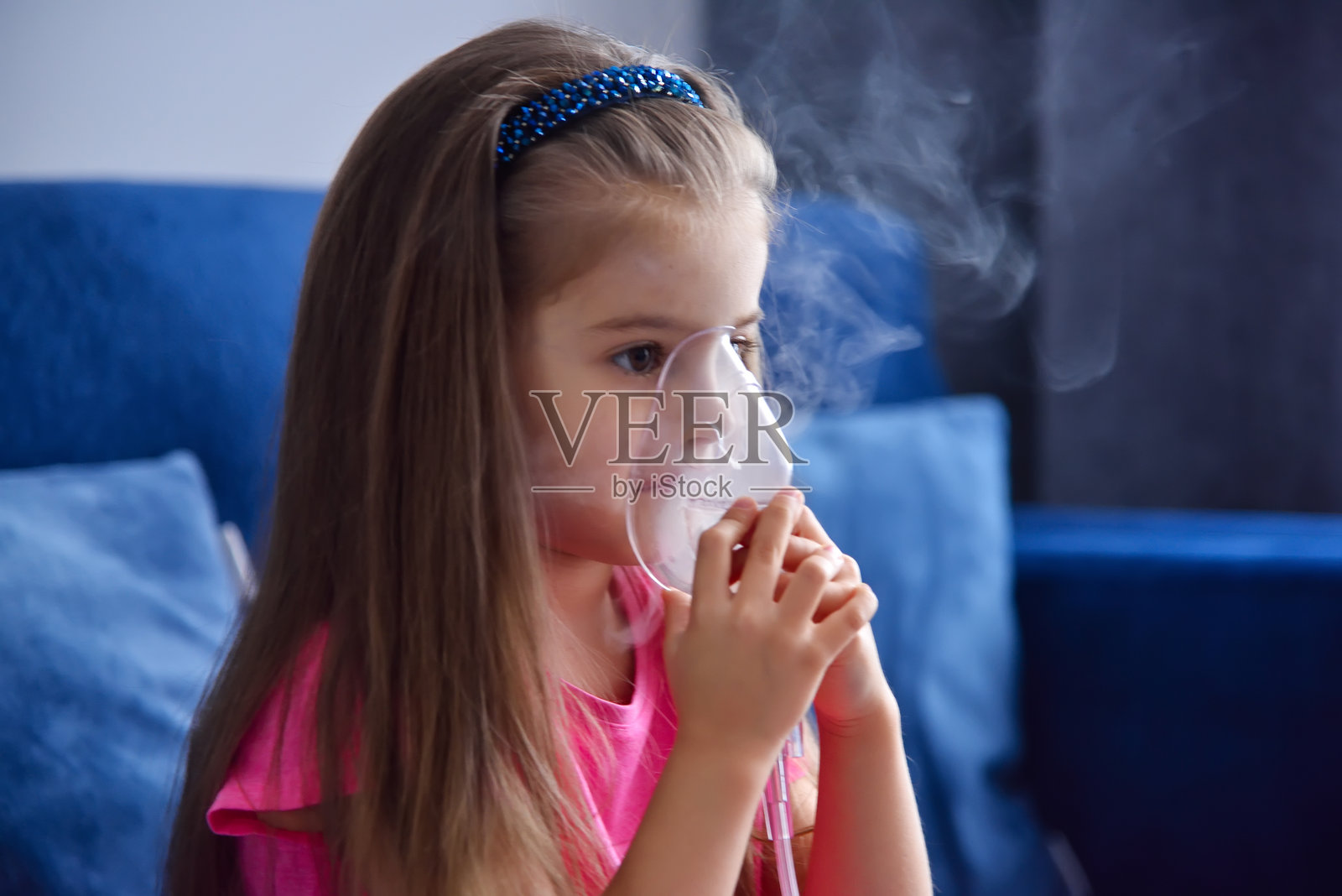 女孩坐在沙发上使用雾化器。照片摄影图片