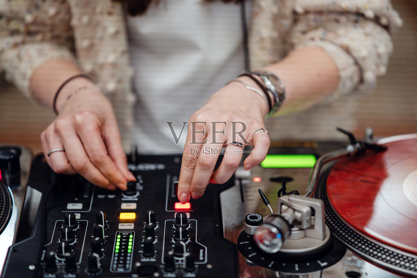 女性DJ在现场活动中使用唱盘和混音器混音音乐照片摄影图片