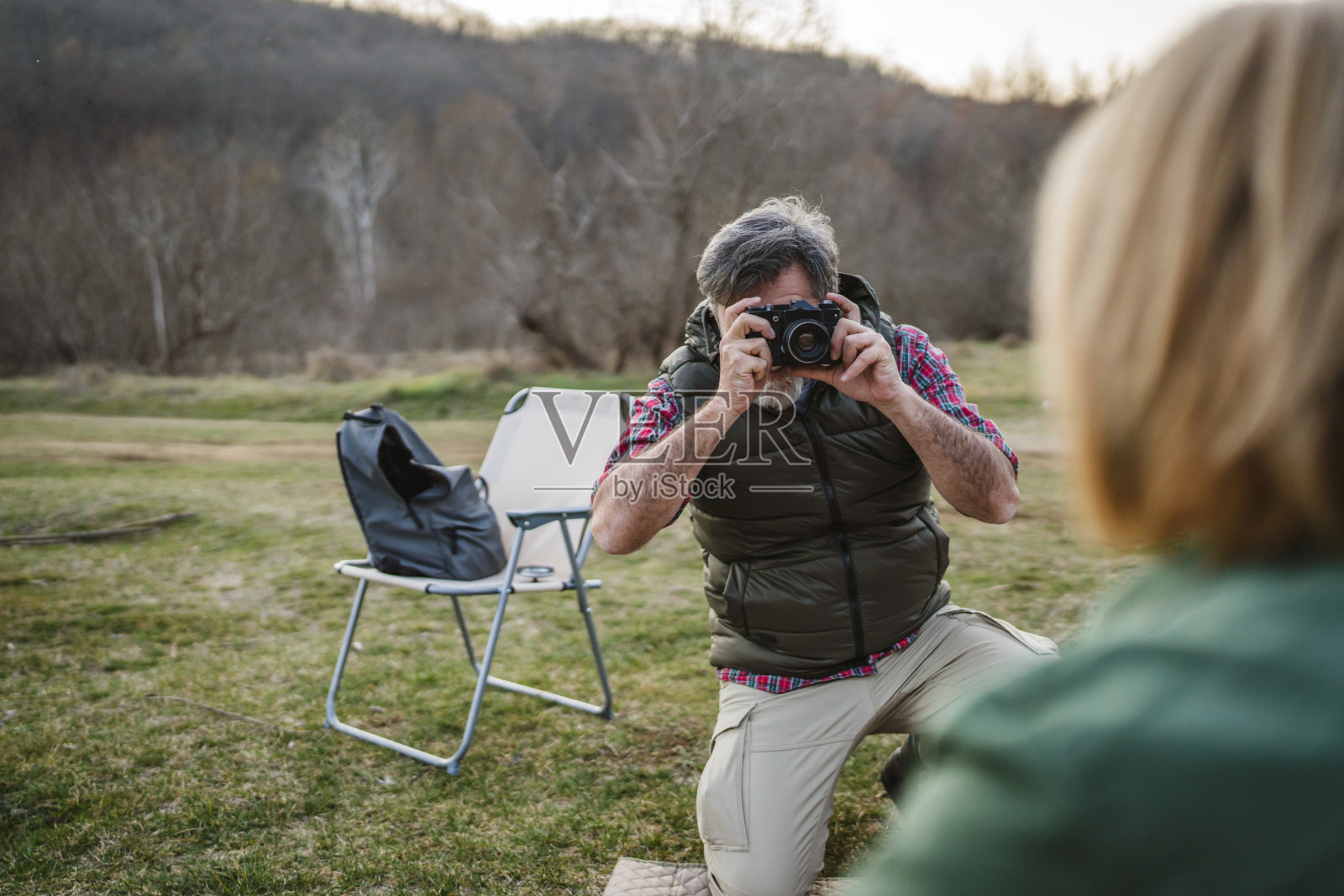 成熟的丈夫在帐篷附近为他的妻子拍照，露营旅行中。照片摄影图片