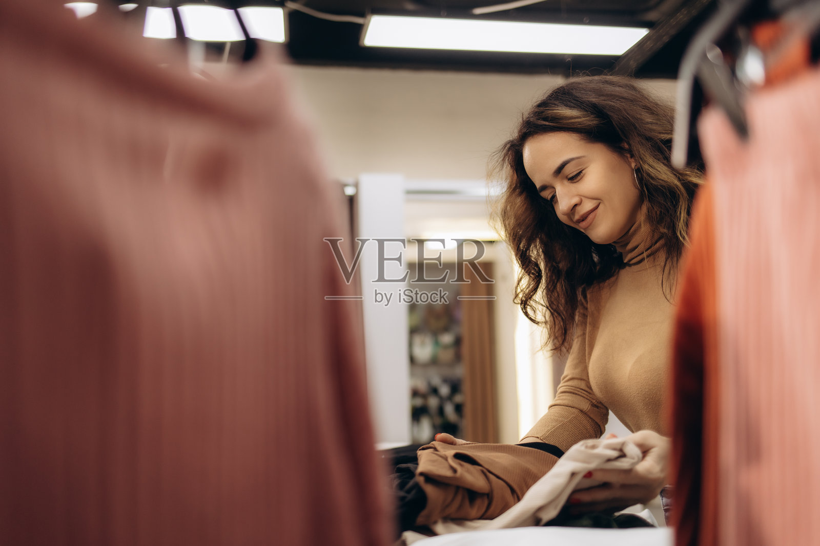 微笑的女性在时尚零售环境中整理衣物照片摄影图片