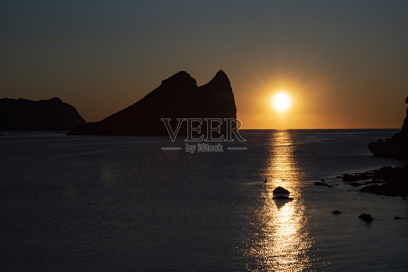 西班牙阿吉拉斯的海上日出，背景是弗拉伊尔岛照片摄影图片