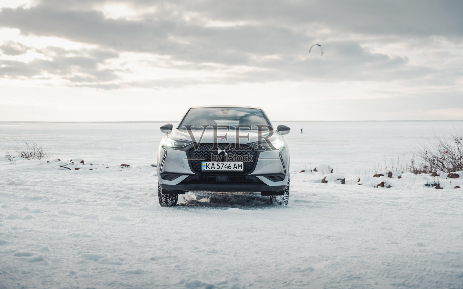 银色汽车停在巨大的冰冻湖边。照片摄影图片