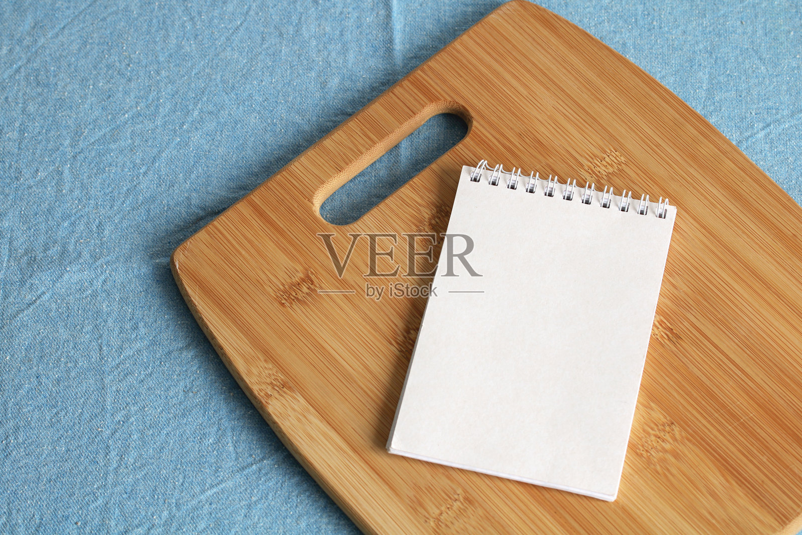 木制砧板上的笔记本，放在蓝色桌布上：食谱和烹饪概念照片摄影图片