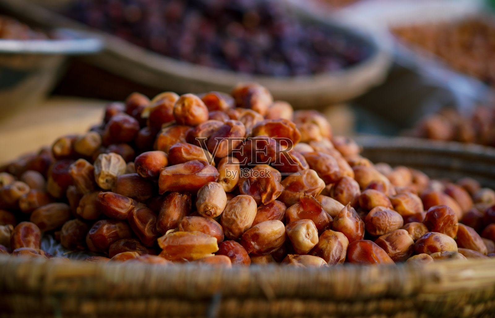 新鲜枣的特写，放在编织篮中，背景是户外市场上各种干枣。照片摄影图片