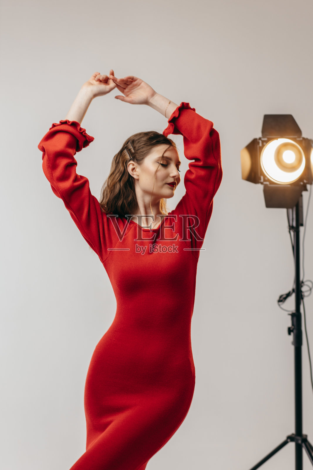 穿着红色裙子的年轻女孩在白色背景的摄影棚里照片摄影图片