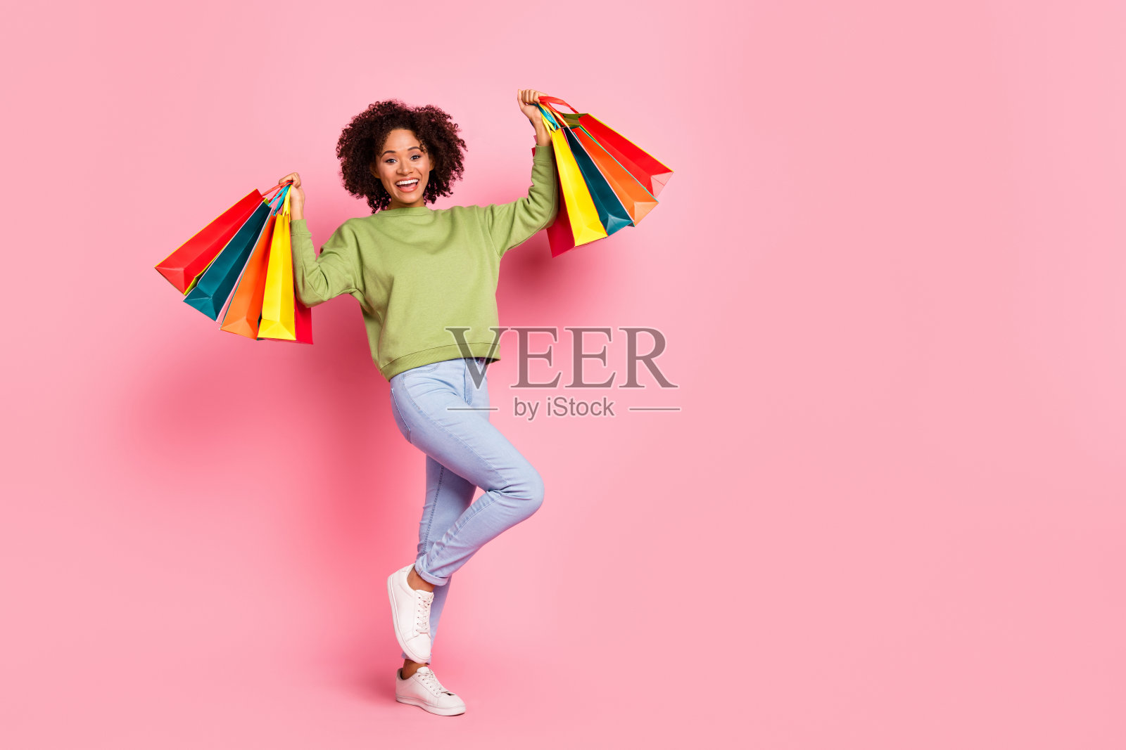 年轻快乐的女孩手持购物袋，站在礼品店前，背景为粉色。照片摄影图片