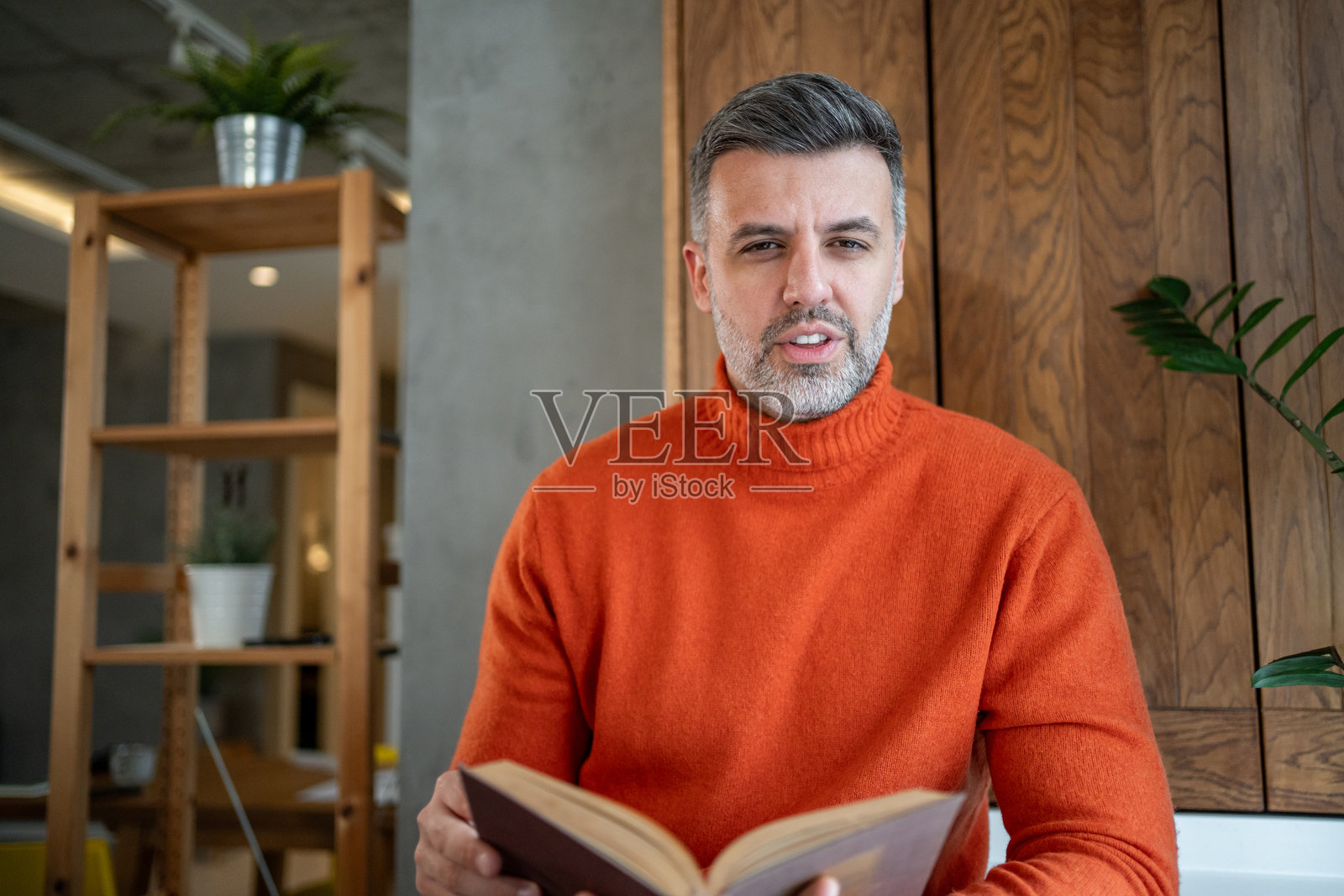 中年男子正在阅读一本书并看向镜头照片摄影图片