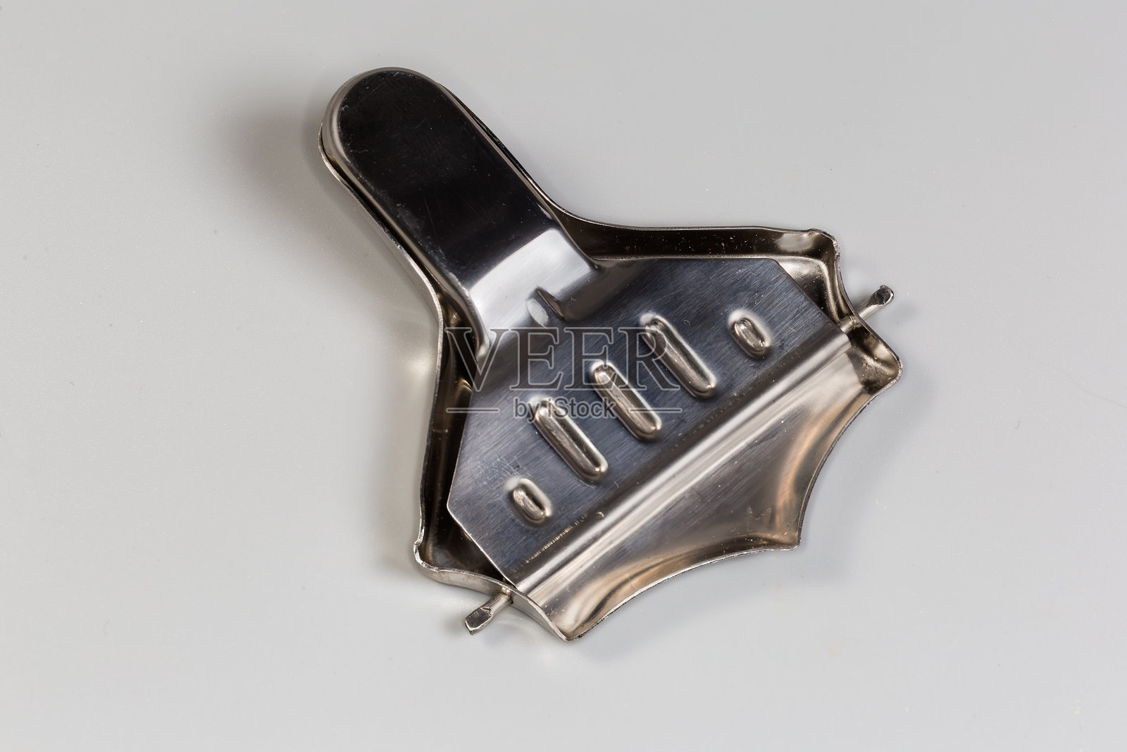 灰色背景上的小型手持不锈钢柠檬榨汁器照片摄影图片