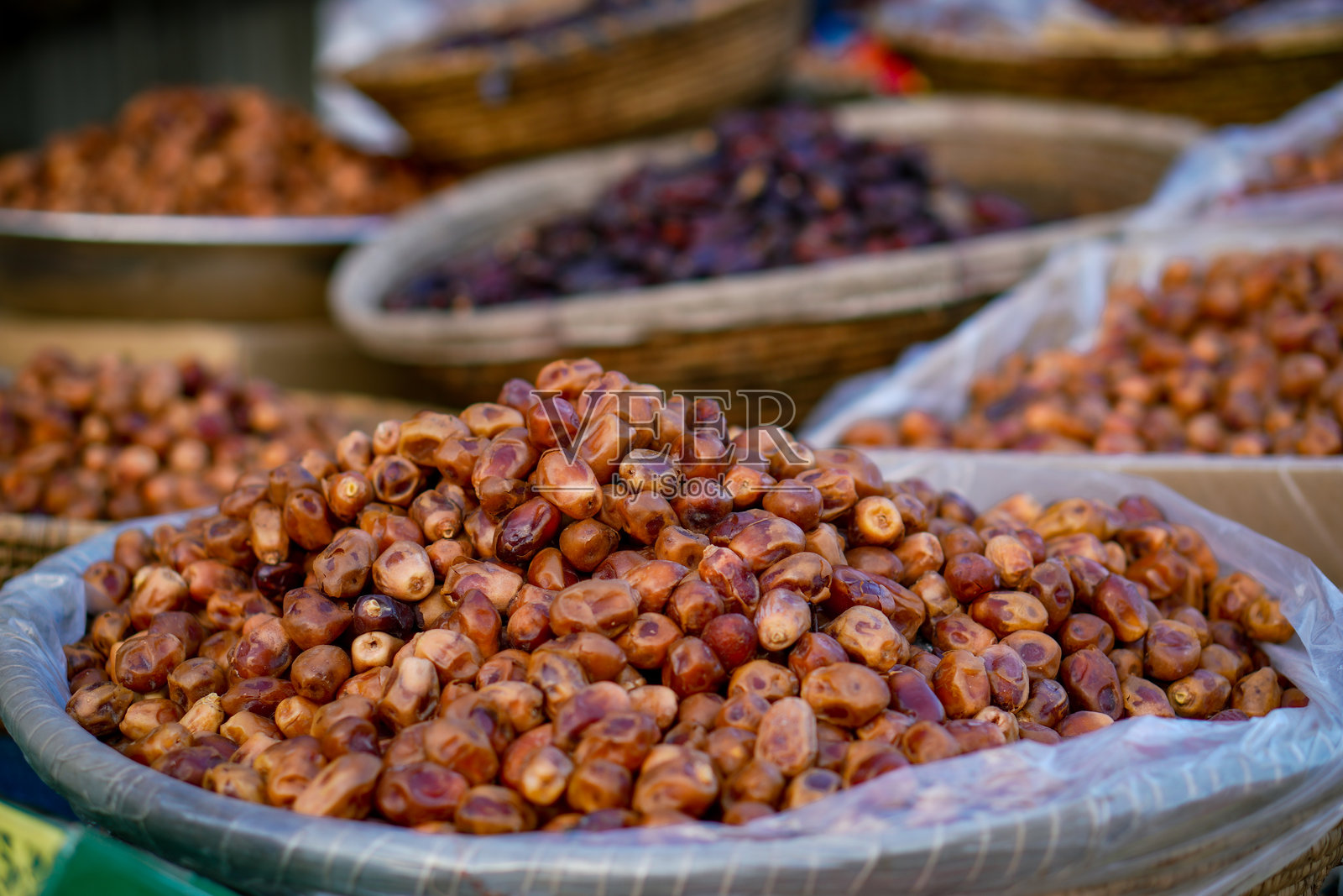 市场摊位上用塑料衬里的篮子里摆放着各种新鲜和干燥的枣子。照片摄影图片