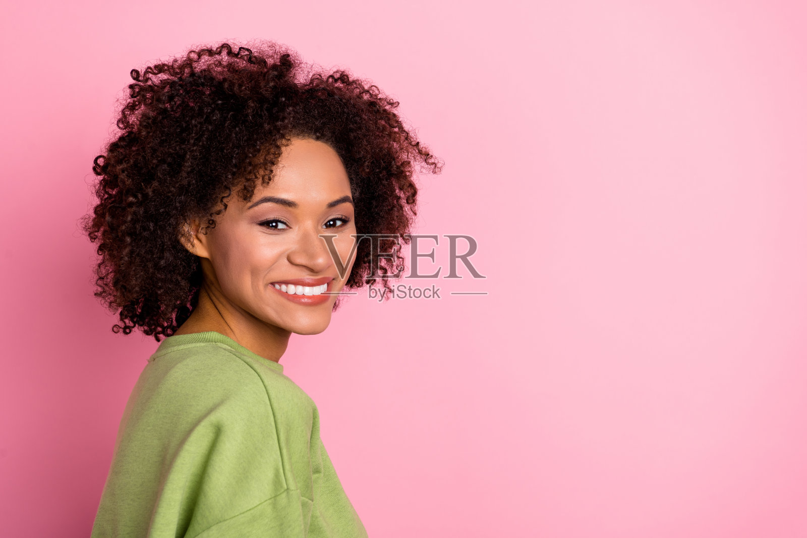 侧面肖像的迷人快乐波浪卷发女孩，空白空间，背景为粉色柔和色调照片摄影图片