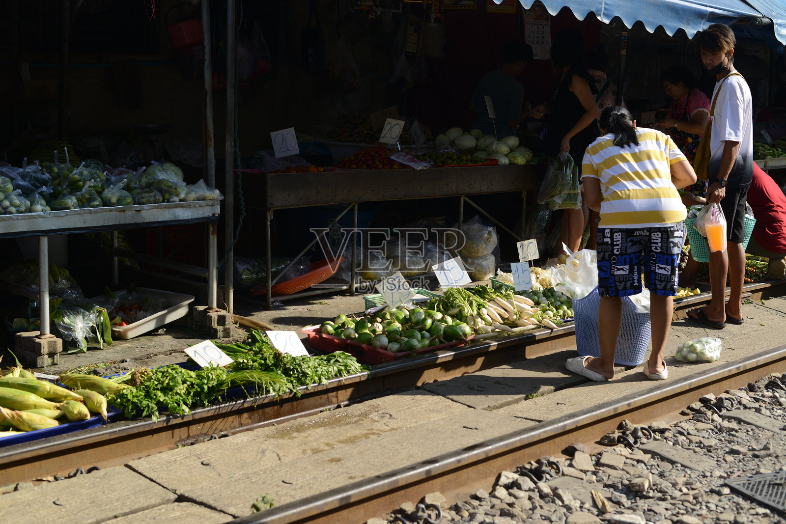 在马哈查伊车站,摊贩沿铁路出售蔬菜、水果和鲜花。当火车到来时,她会保持货架不动,因为它们较低。照片摄影图片