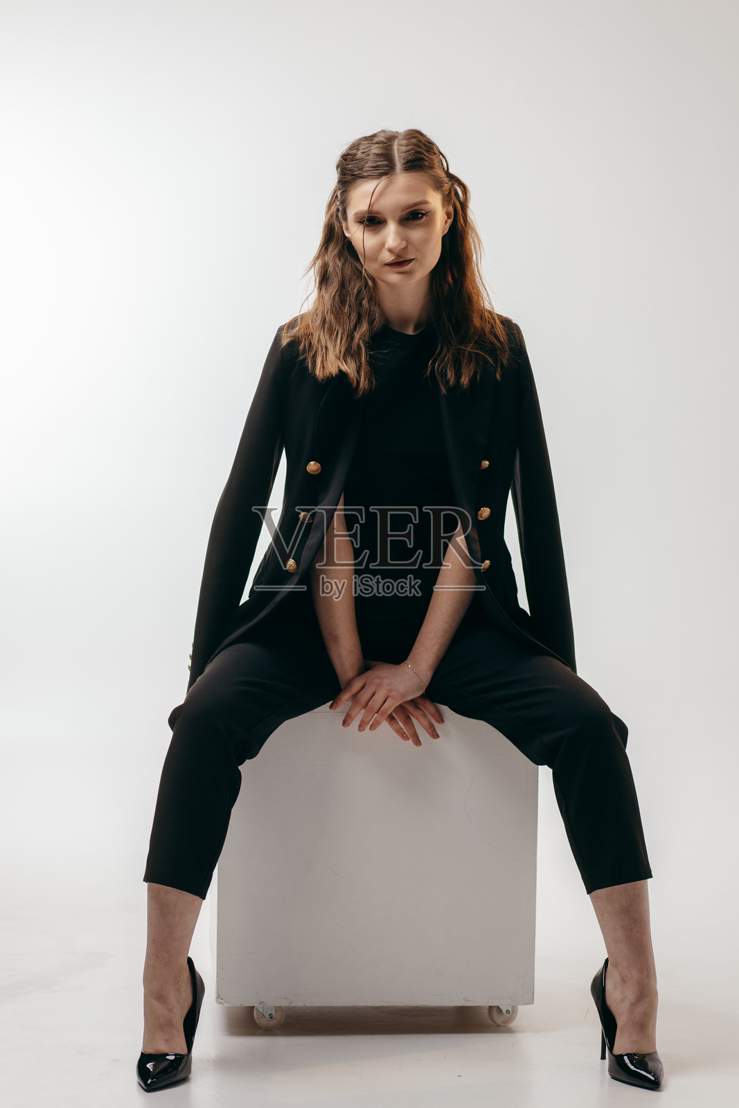 年轻成功的女商人在白色背景的工作室里穿着黑色西装照片摄影图片