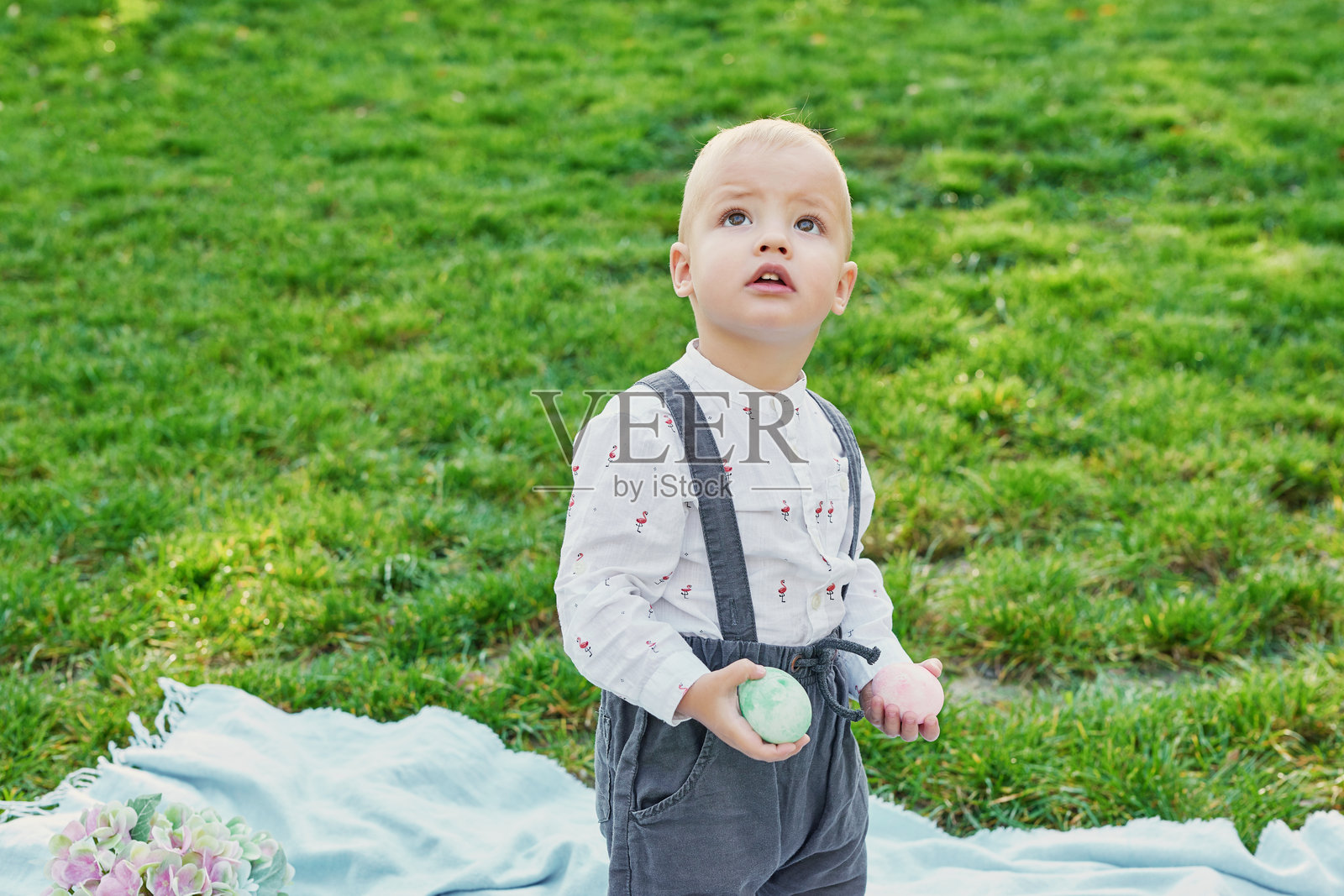 快乐的复活节兔子。孩子在户外玩得很开心。小孩在绿草地上与彩蛋和兔子玩耍。春季假期概念。复活节贺卡模板。复活节小男孩与兔子和彩蛋。照片摄影图片