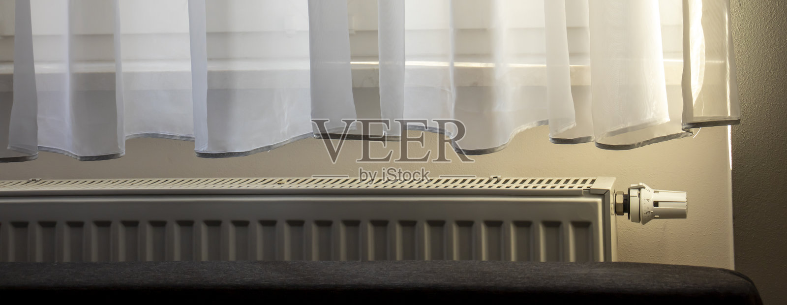 一个宁静的室内场景，轻薄的窗帘柔和地散射自然光，营造出宁静的氛围。非常适合家居装饰或室内设计主题。照片摄影图片