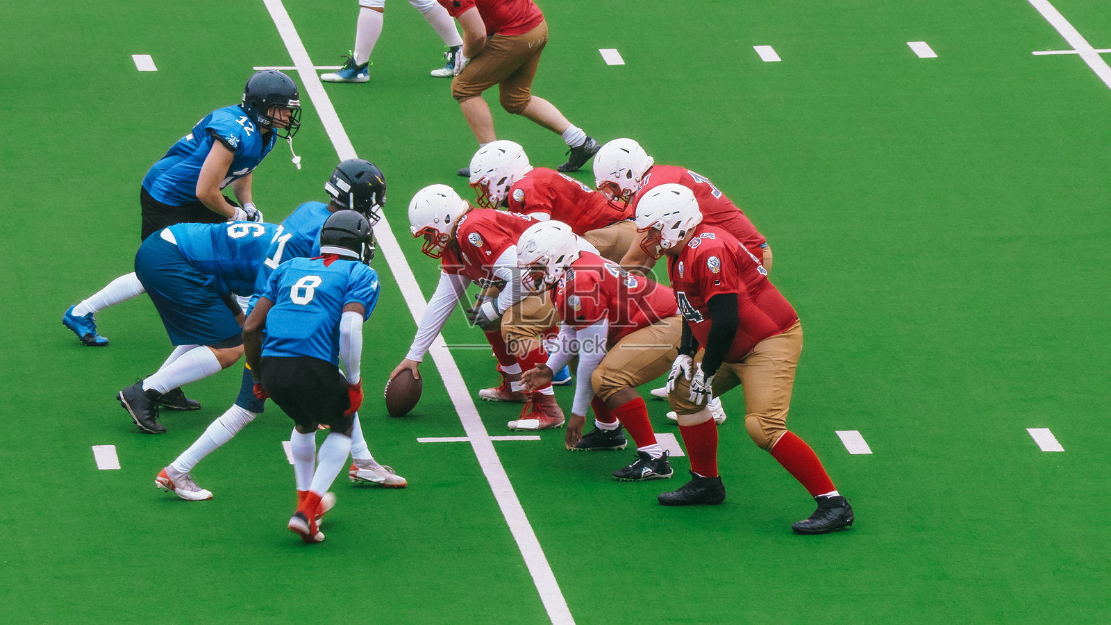 两支多元化的运动队在比赛开始时就位。球准备好开始比赛。球员们准备向前冲，而对方球队则试图阻止他们。照片摄影图片