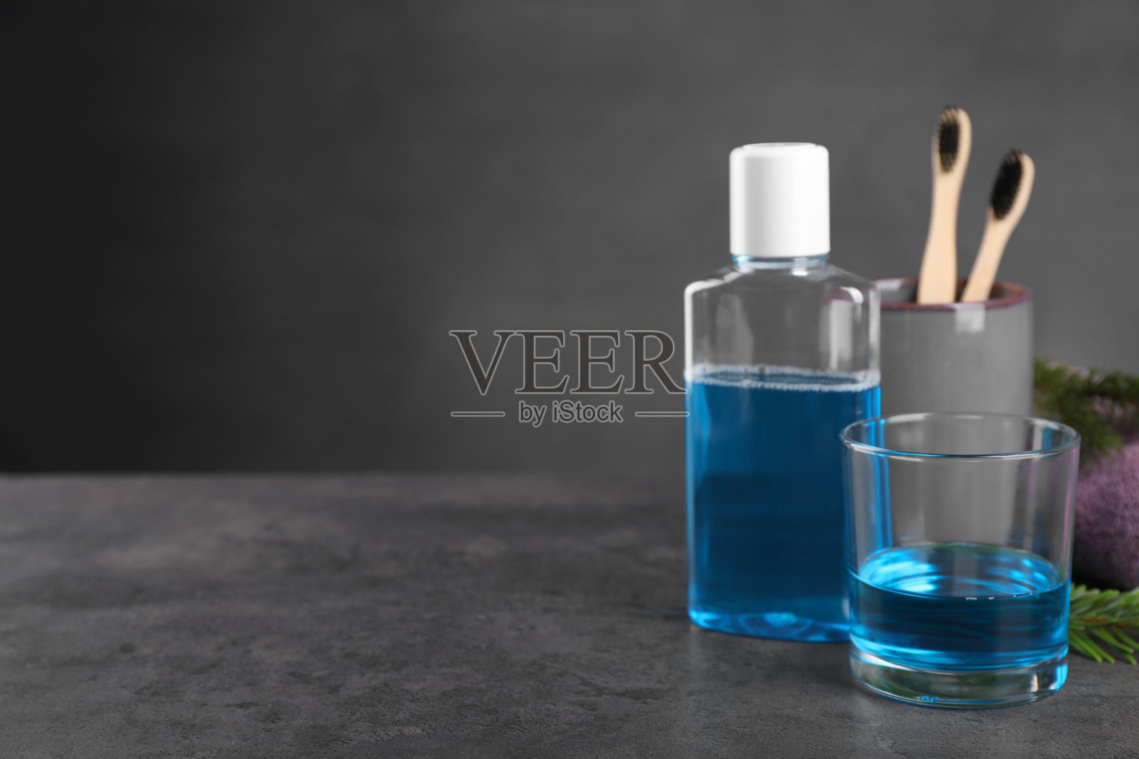 深色纹理桌面上的新鲜漱口水，玻璃杯和瓶子特写。留有文字空间。照片摄影图片