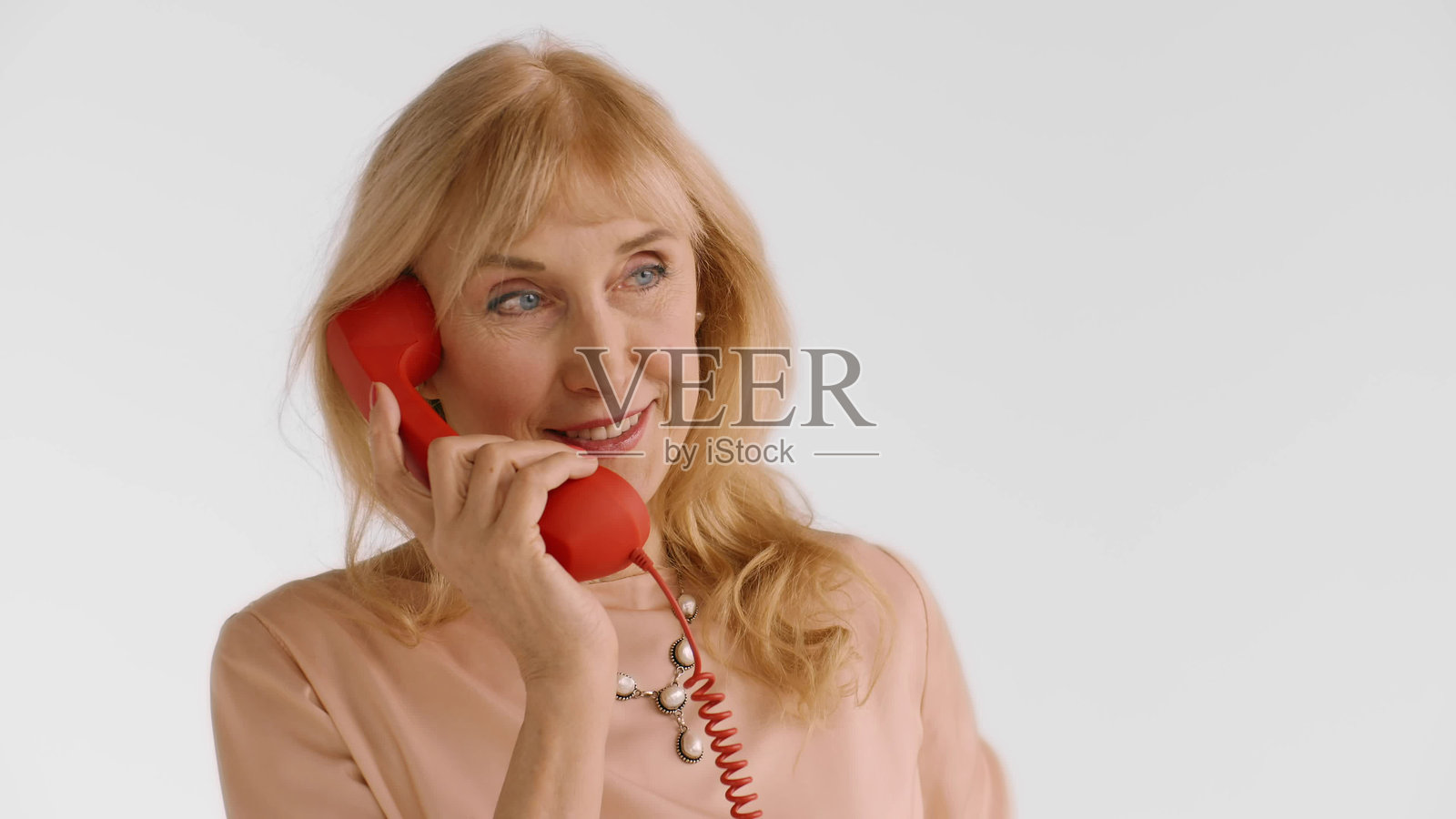 优雅的金发老妇人在白色背景上使用红色座机电话交谈照片摄影图片
