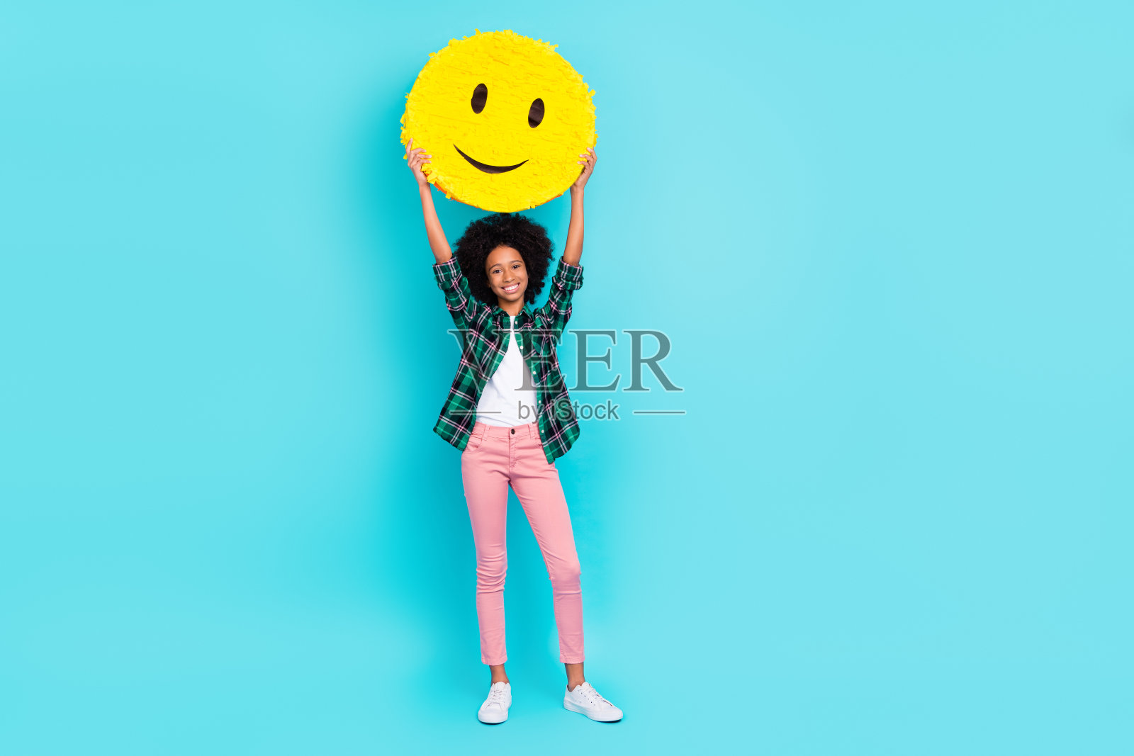 积极友好的女士展示微笑表情，举起双手，穿着格子衬衫，背景为青色。照片摄影图片